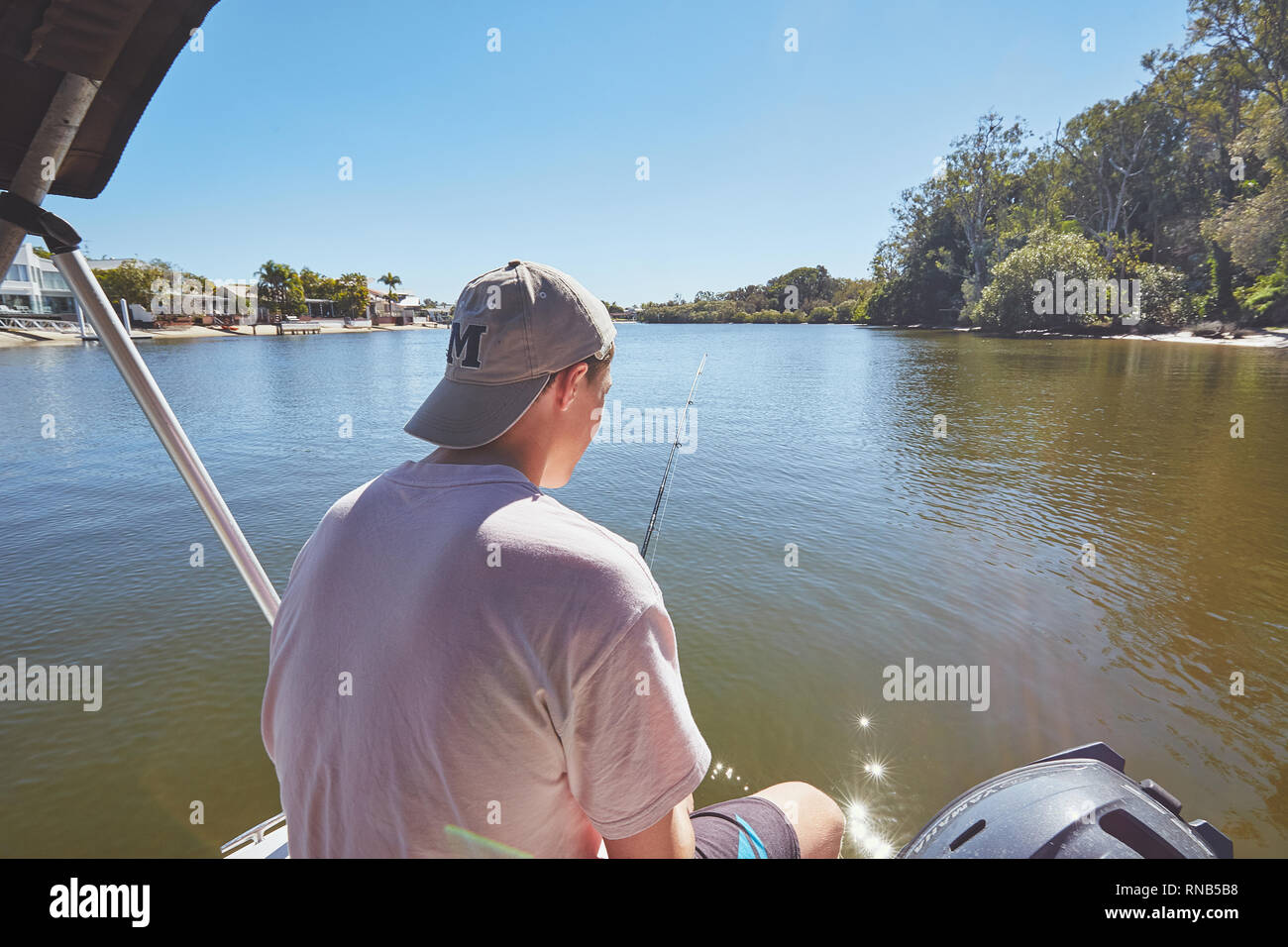 Teenage maschio su una piccola barca, pesca, su un fiume in Queensland, Australia Foto Stock