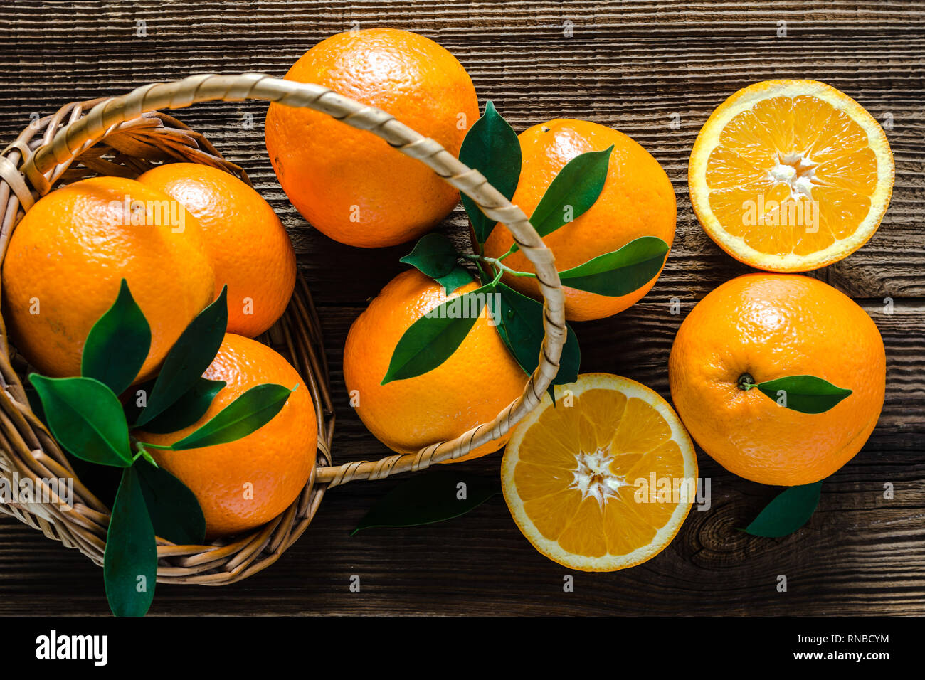 Arance fresche in un cesto su un tavolo di legno. Frutta di arancia, vista dall'alto. Foto Stock