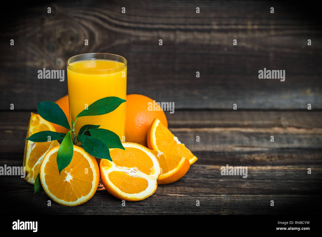 Il succo d'arancia fresco in un bicchiere con spremuta di arance sul tavolo di legno Foto Stock