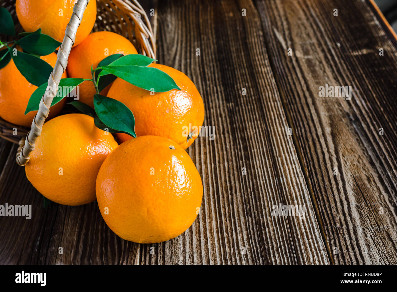 Fattoria fresco frutta di arancia in un cestino sul tavolo di legno Foto Stock