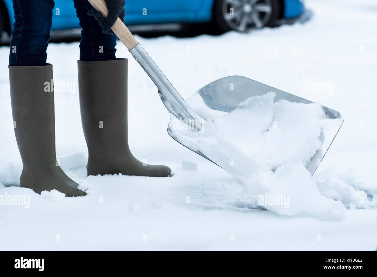 Donna Clearing neve invernale dal percorso con pala Foto Stock