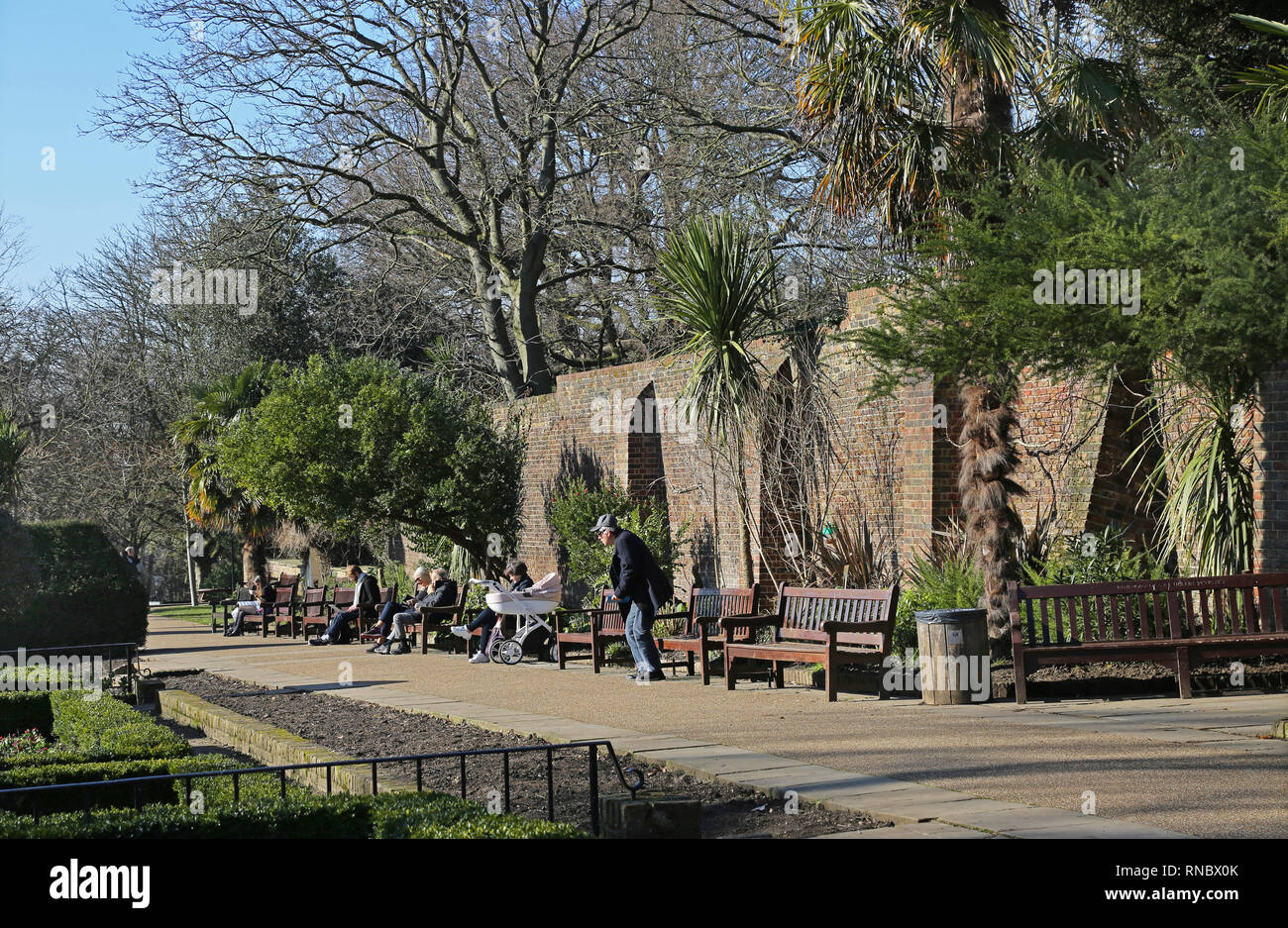 Persone godetevi il sole in una giornata invernale e nella zona londinese di Holland Park giardini di Kensington, una delle città più ricche aree. Foto Stock