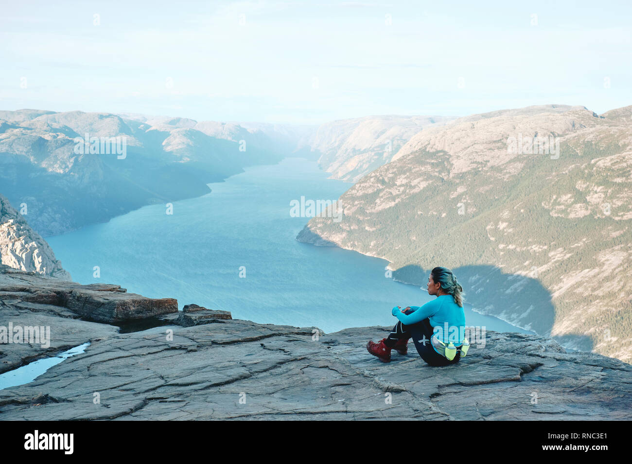 Una ragazza escursionista in appoggio e godendo della vista sulla parte superiore del Pulpito Rock / Prekestolen o Prekestolen in Norvegia Foto Stock