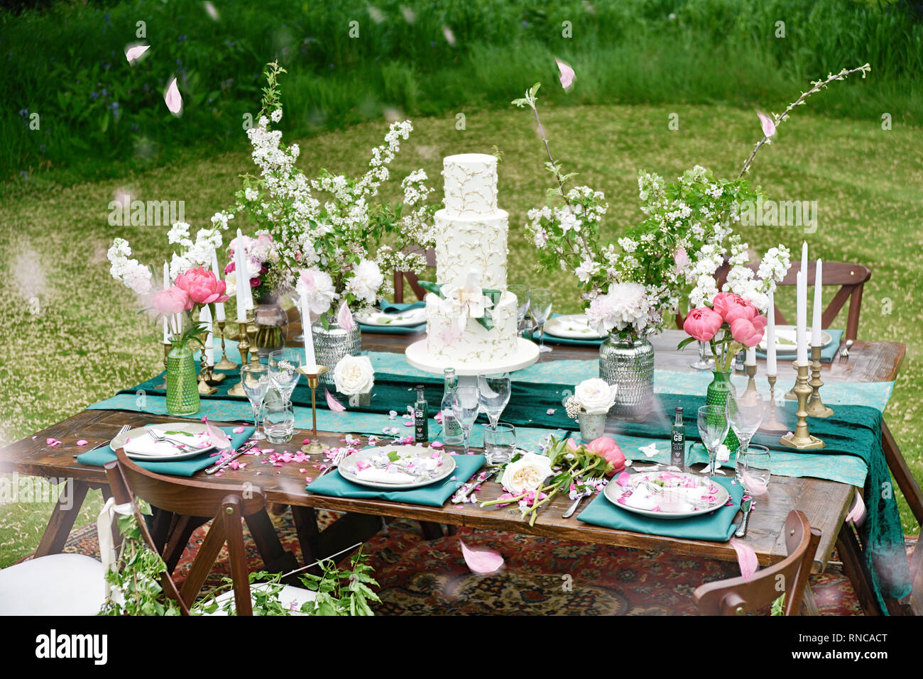 Un bellissimo tavolo esterno display, con un sacco di fiori di primavera in vari colori- situato in un verde giardino erboso su un luminoso giorno Foto Stock