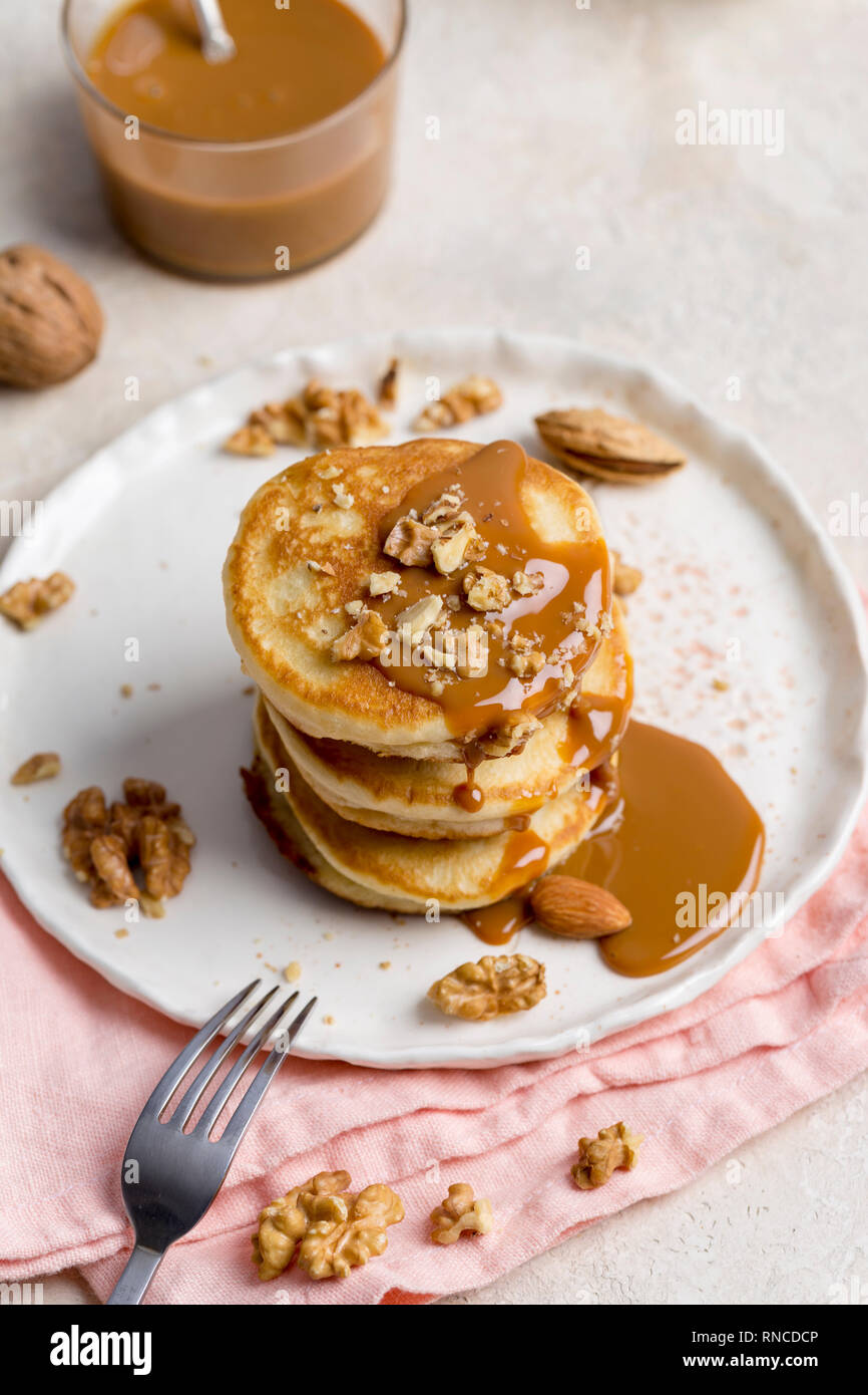Pila di pancake con caramello e noci sulla piastra bianca. Concetto di cibo festoso su Martedì grasso Foto Stock