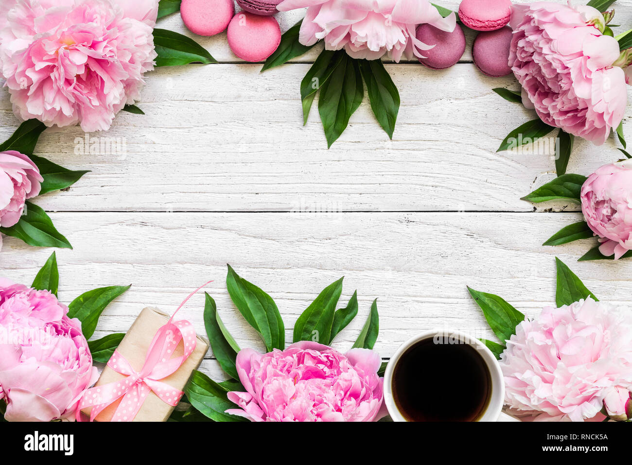 Telaio realizzato in rosa peonia fiori, amaretti, una tazza di caffè e confezione regalo. molla sfondo. vista dall'alto. flat laici. Il concetto di matrimonio Foto Stock
