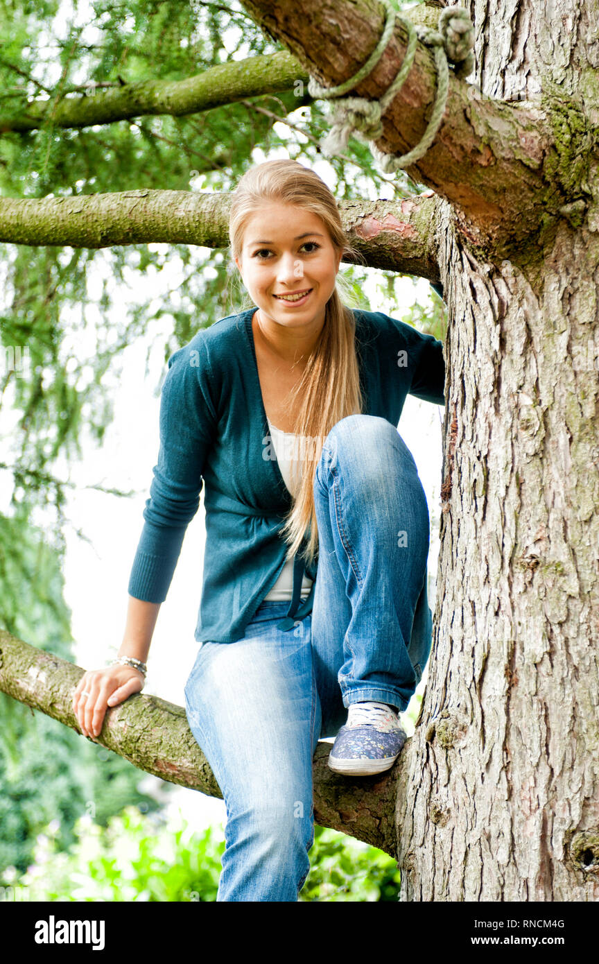 Junge Frau mit langen Haaren blondn sitzt auf einem Baum [(c) Dirk A. Friedrich Foto Stock