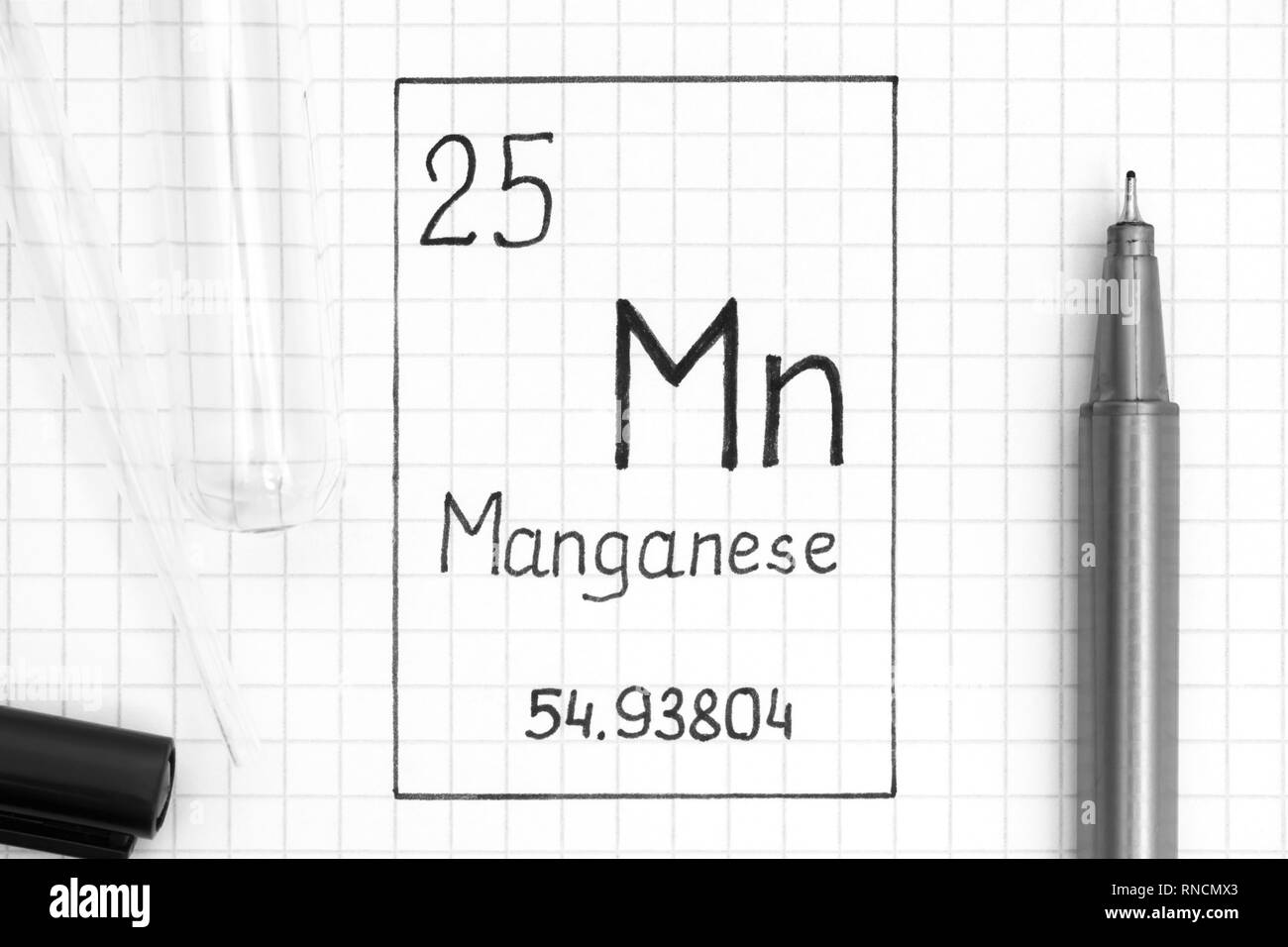 Tavola periodica degli elementi. La grafia elemento chimico manganese Mn con la penna nera, tubo di prova e la pipetta. Close-up. Foto Stock