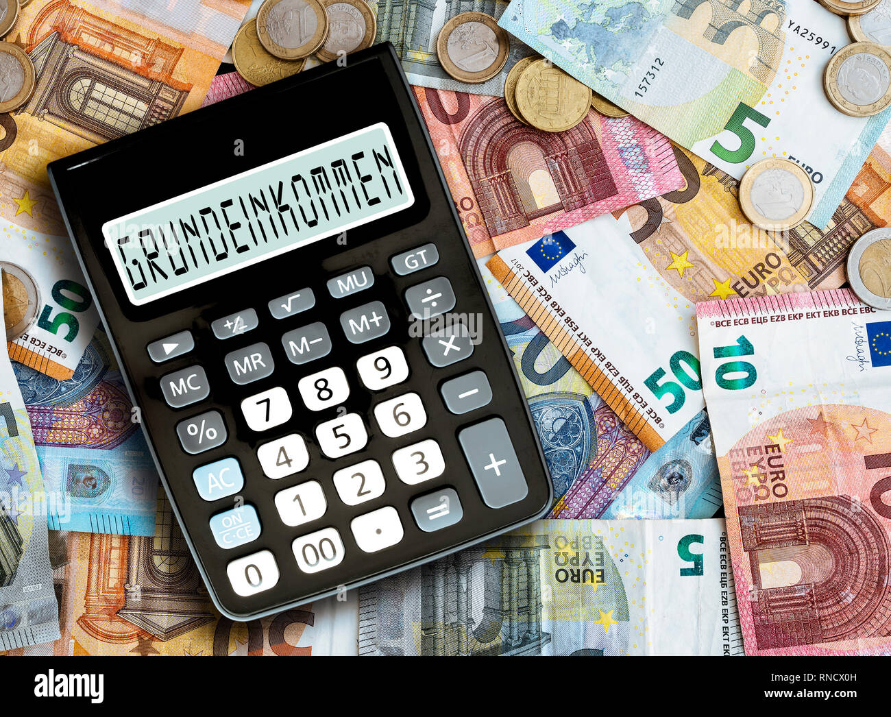 Parola tedesca GRUNDEINKOMMEN (reddito base) scritto sul display della calcolatrice tascabile contro il denaro sul tavolo Foto Stock