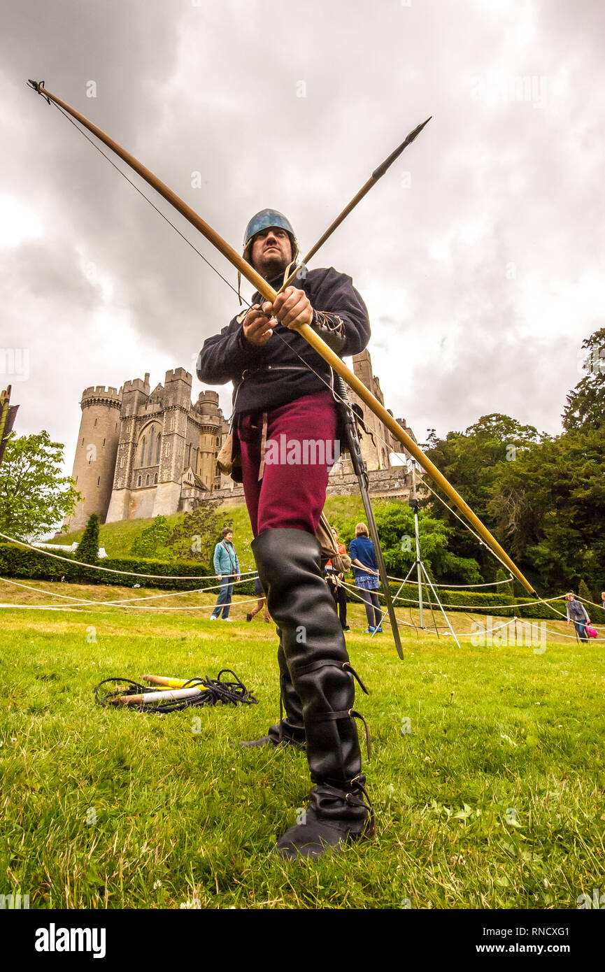 Un arciere in abito medievale siti lungo il suo arco durante una rievocazione storica da Raven Tour Storia Vivente Gruppo Arundel Castle ©Julia Claxton Foto Stock