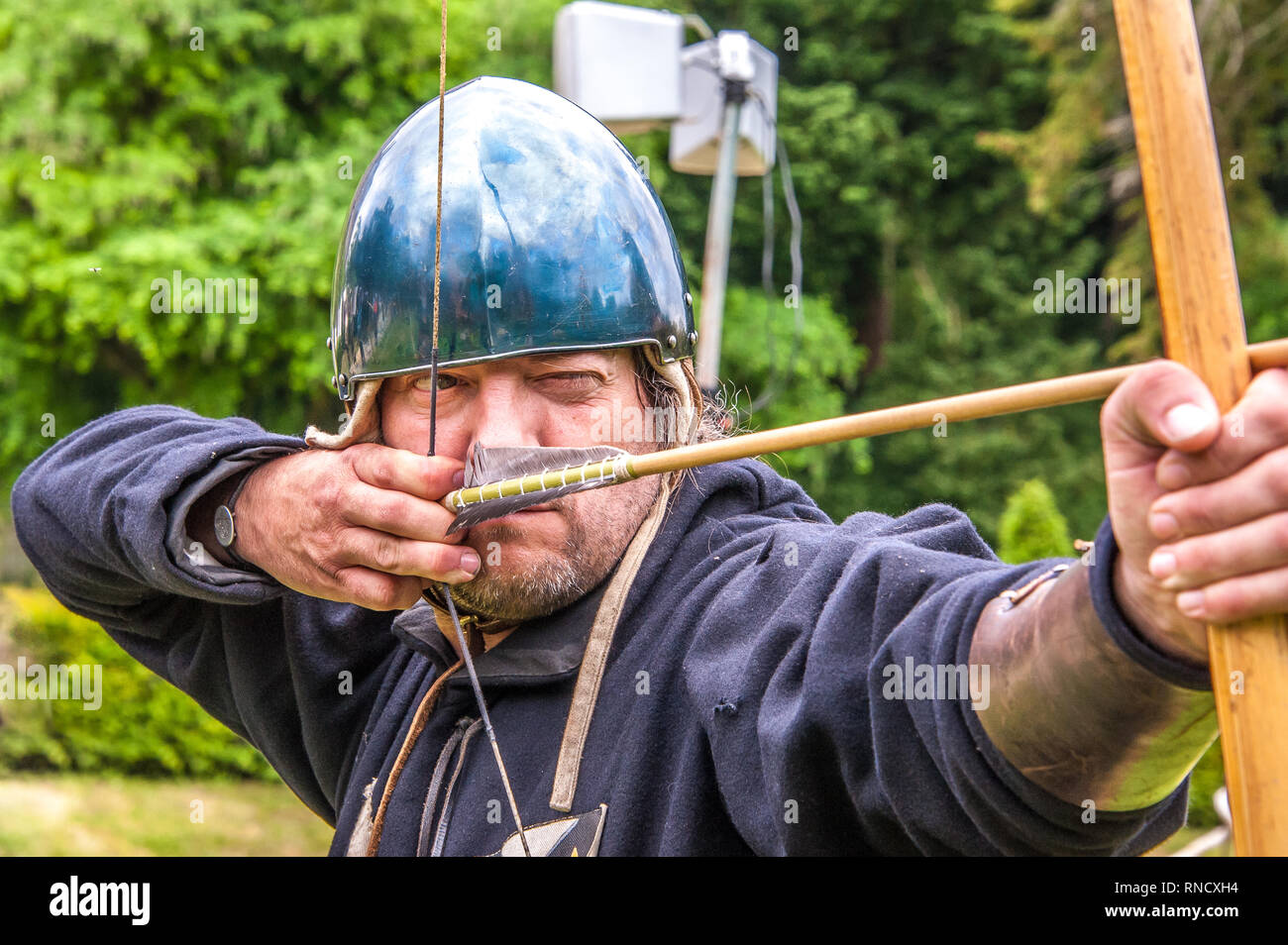 Un arciere in abito medievale siti lungo il suo arco durante una rievocazione storica da Raven Tour Storia Vivente Gruppo Arundel Castle ©Julia Claxton Foto Stock