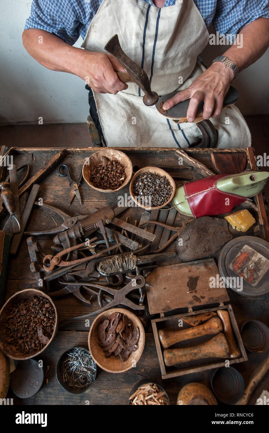 Il calzolaio al suo banco da lavoro. Vari strumenti e lo strumento sono collocati sul banco di lavoro Foto Stock