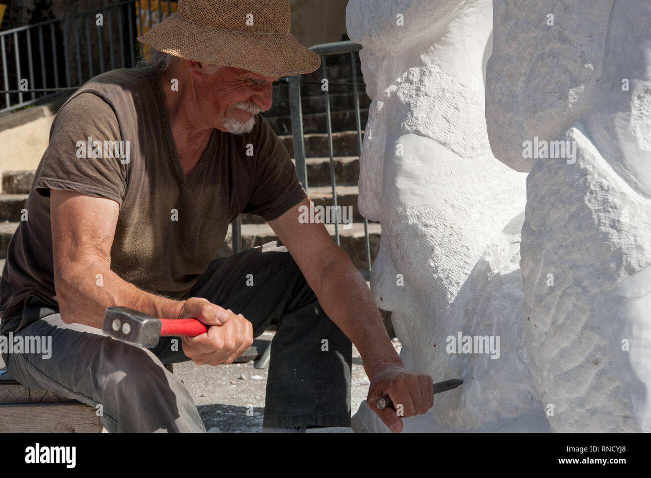 Senior di lavoro dello scultore outdoor presso la scultura in marmo nella sua bottega con martello e scalpello Foto Stock