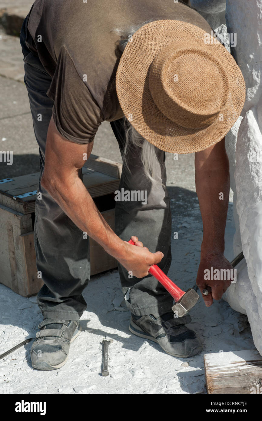 Senior di lavoro dello scultore outdoor presso la scultura in marmo nella sua bottega con martello e scalpello Foto Stock