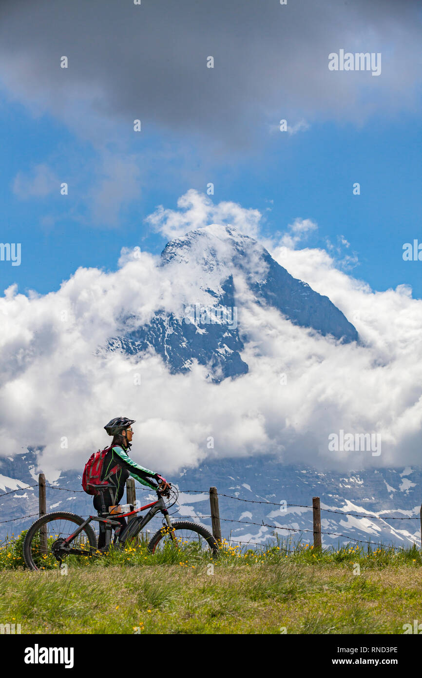 Bella e sempre giovane donna Senior in sella il suo e-mountainbike al di sotto dell'Eiger northface, nelle alpi svizzere nei pressi di Grindelwald Foto Stock