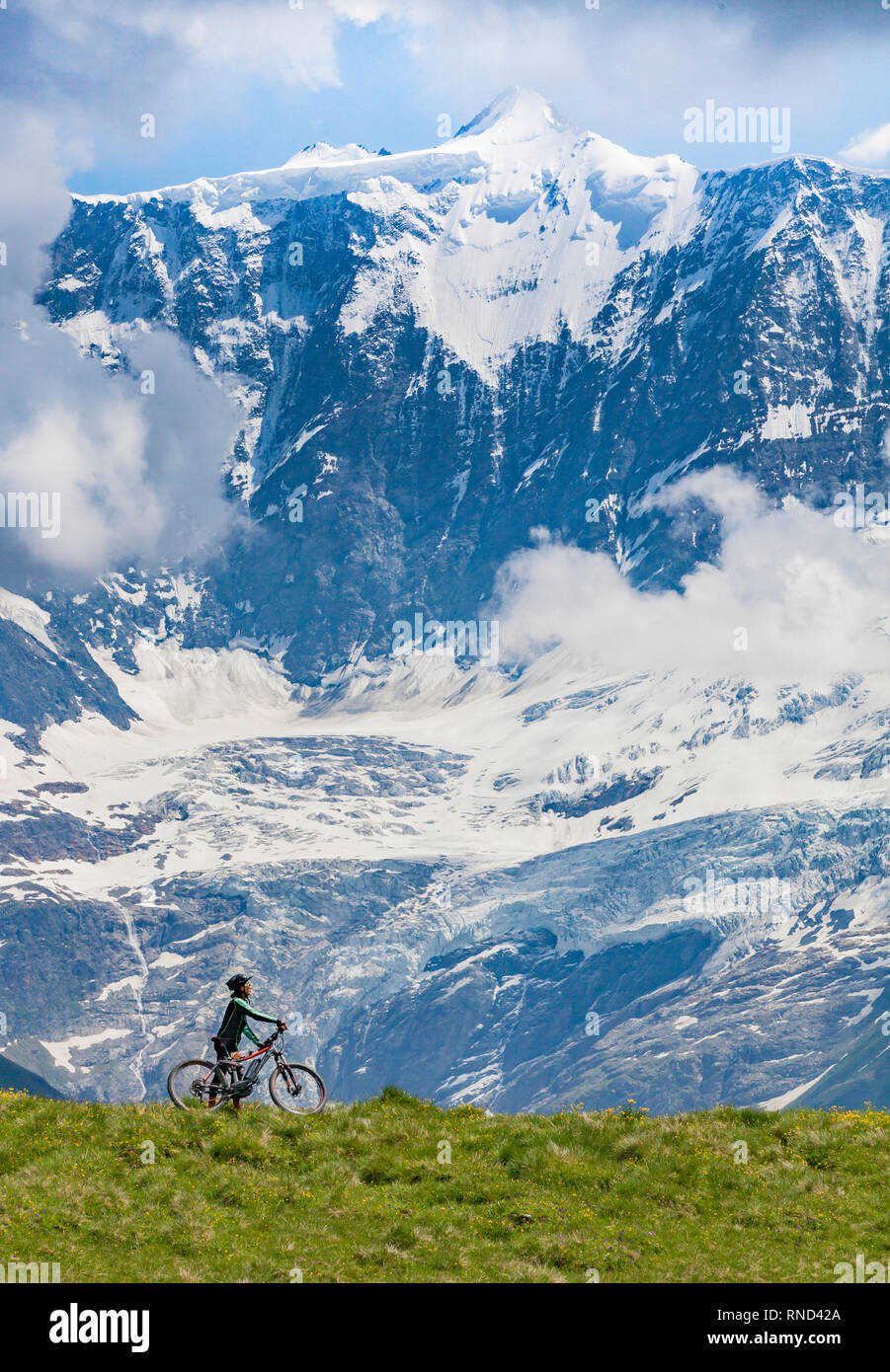 Bella e sempre giovane donna Senior in sella il suo e-mountainbike al di sotto dell'Eiger northface, vicino a Grindelwald, Berner Oberland, Svizzera Foto Stock