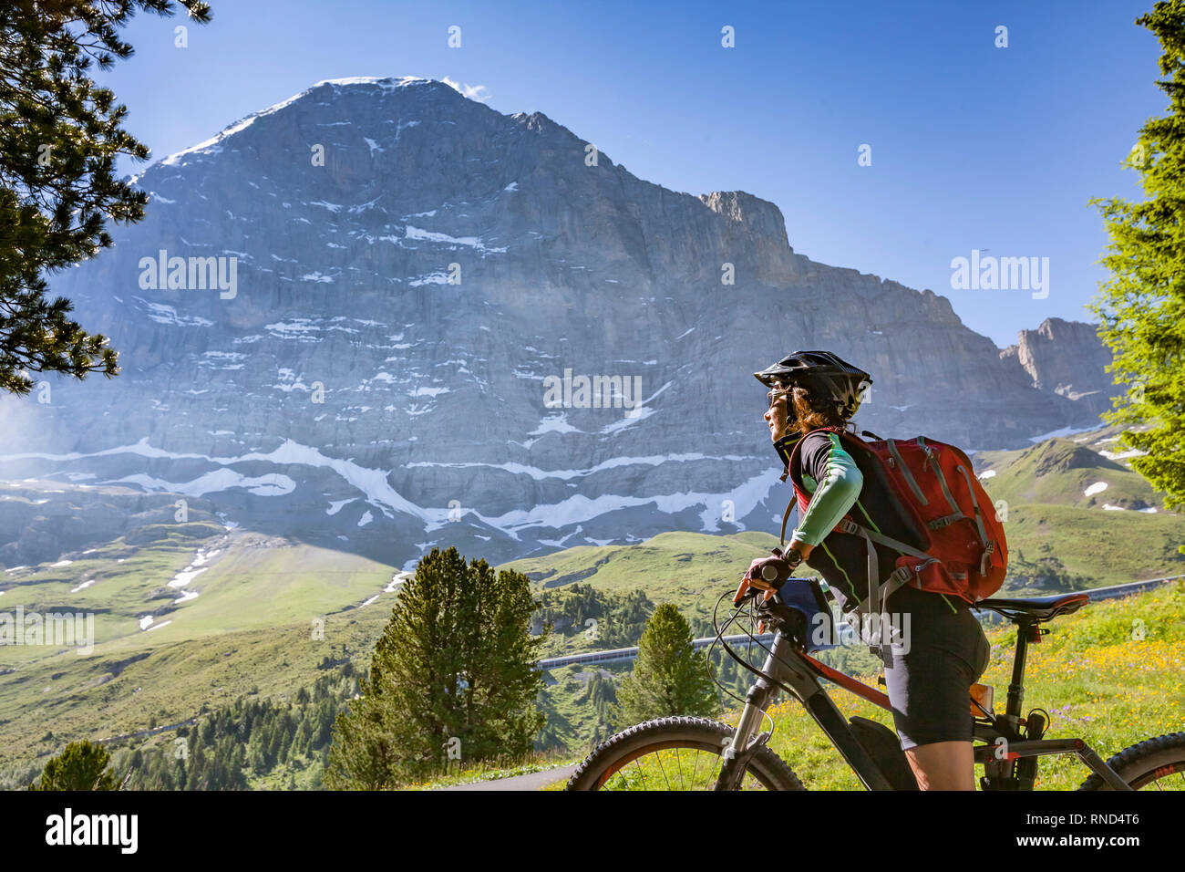 Bella e sempre giovane donna Senior in sella il suo e-mountainbike al di sotto dell'Eiger northface, Jungfrauregion, Svizzera Foto Stock