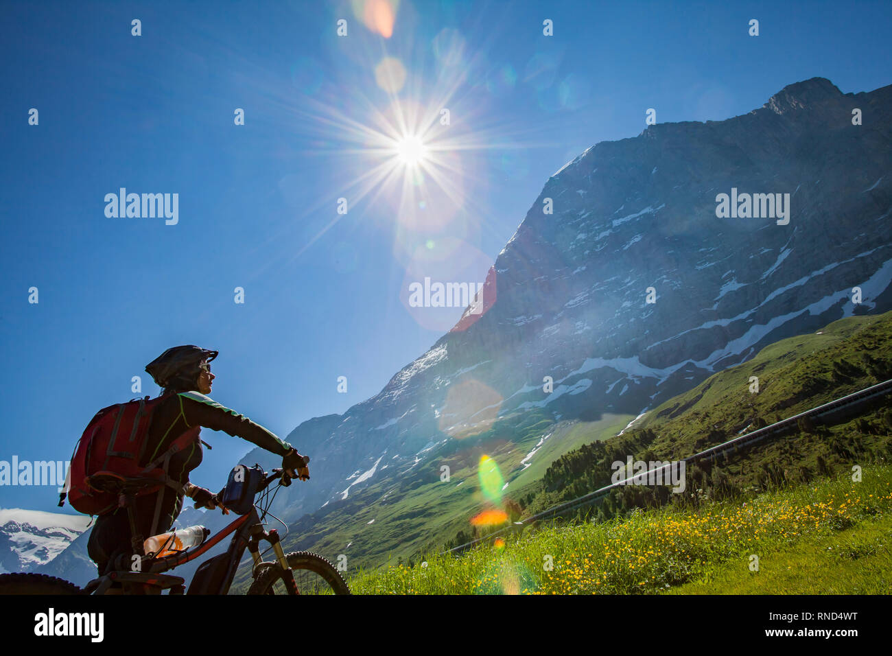 Bella e sempre giovane donna Senior in sella il suo e-mountainbike al di sotto dell'Eiger northface, Jungfrauregion, Svizzera Foto Stock