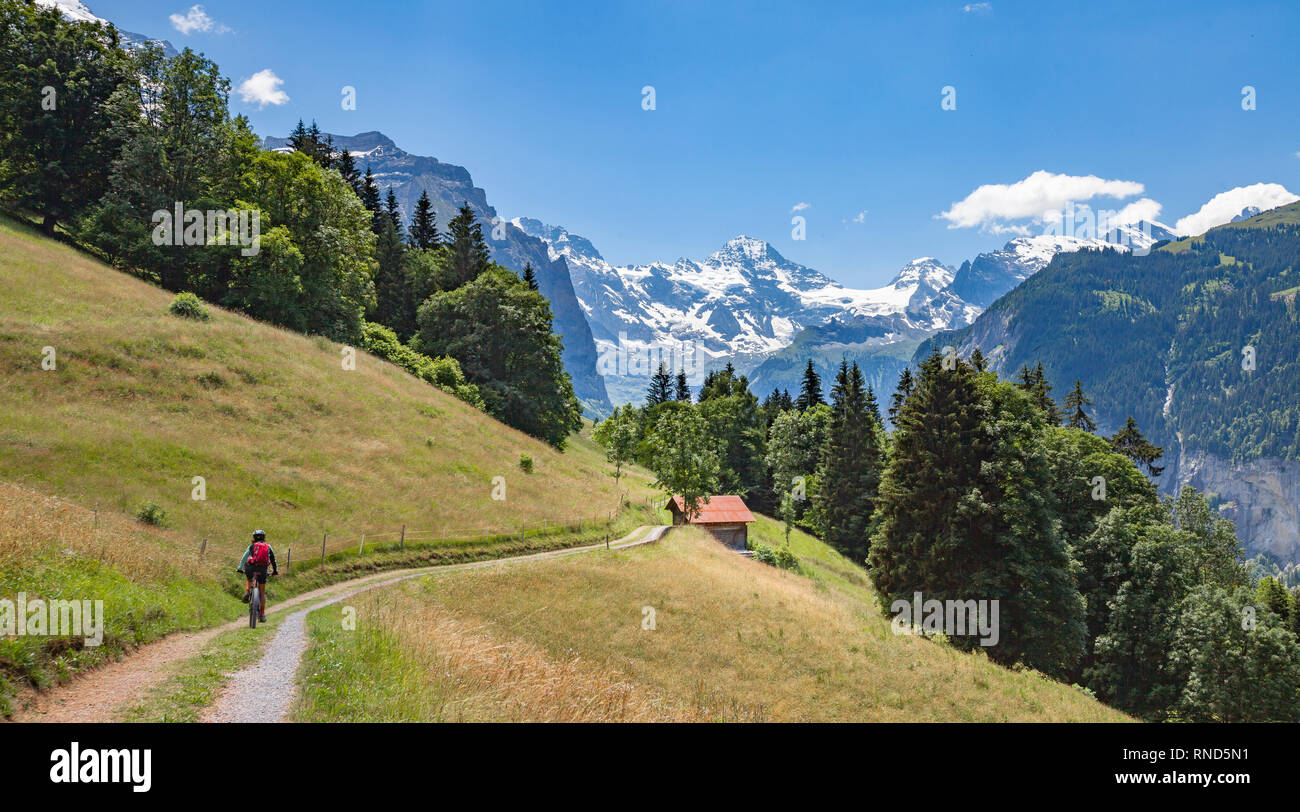 Bella e sempre giovane donna Senior in sella il suo e-mountainbike al di sotto dell'Eiger northface, Jungfrauregion, Svizzera Foto Stock