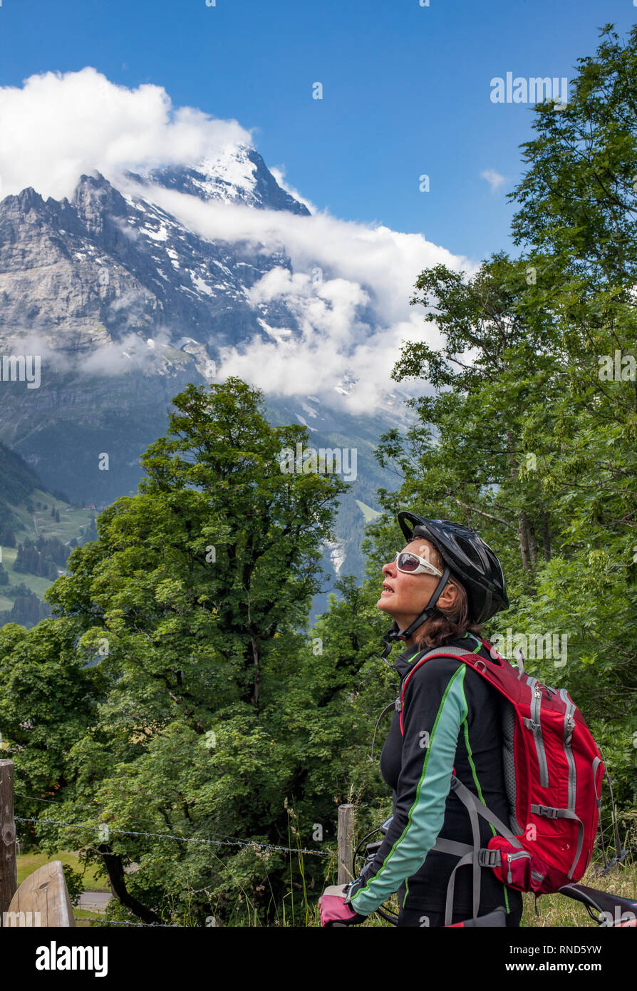 Bella e sempre giovane donna Senior in sella il suo e-mountainbike al di sotto dell'Eiger northface, Jungfrauregion, Foto Stock