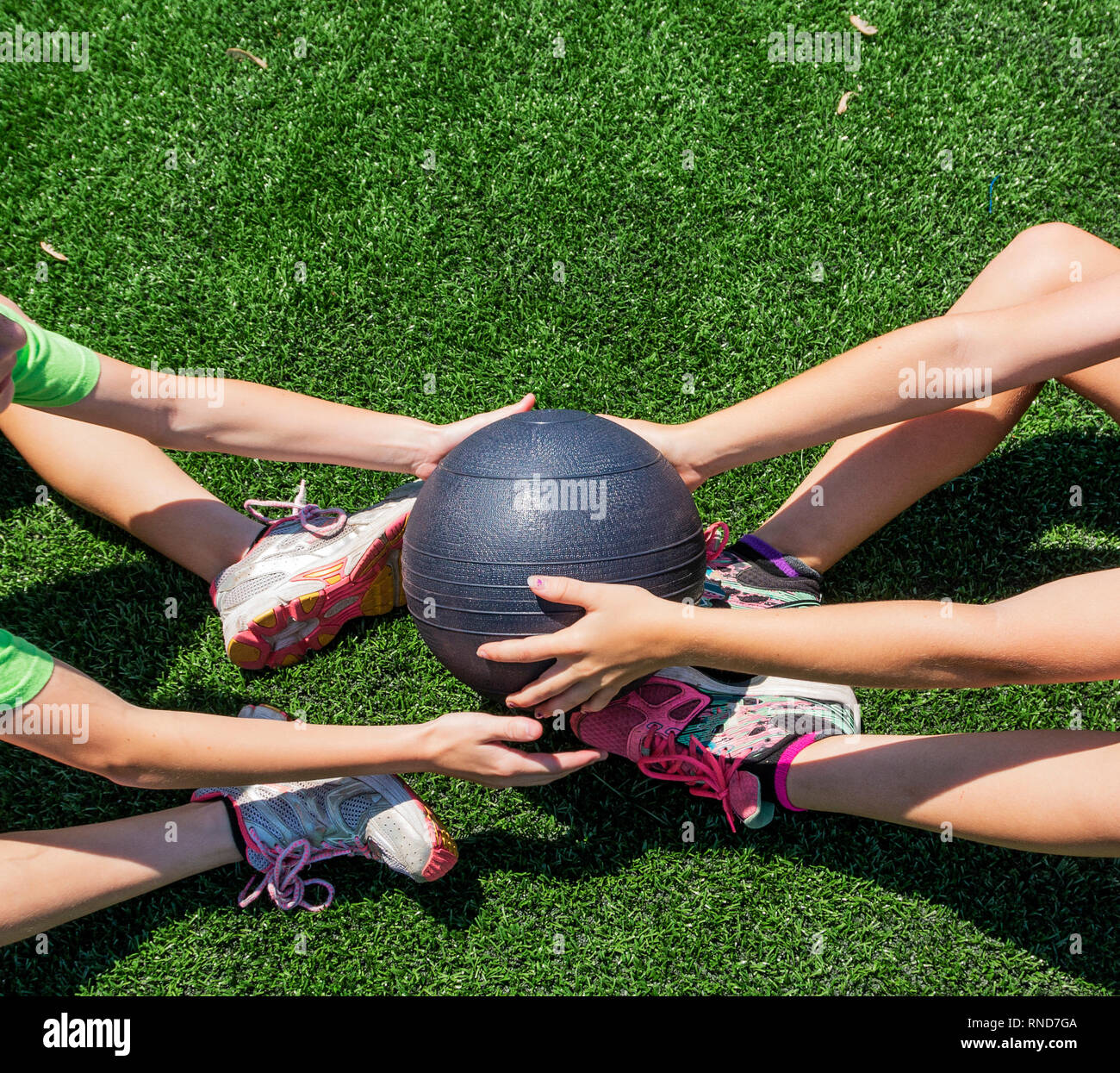 Due giovani atleti stanno passando la palla medica indietro ond via mentre facendo sit ups su un tappeto erboso verde campo. Foto Stock