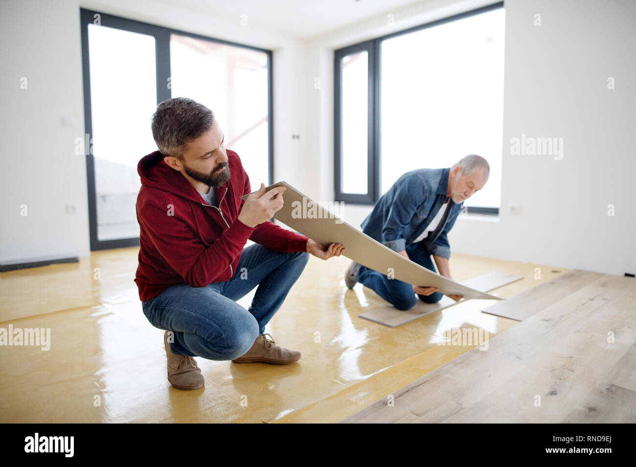 Un uomo maturo con il suo anziano padre la posa di pavimenti in vinile, un nuovo concetto di casa. Foto Stock