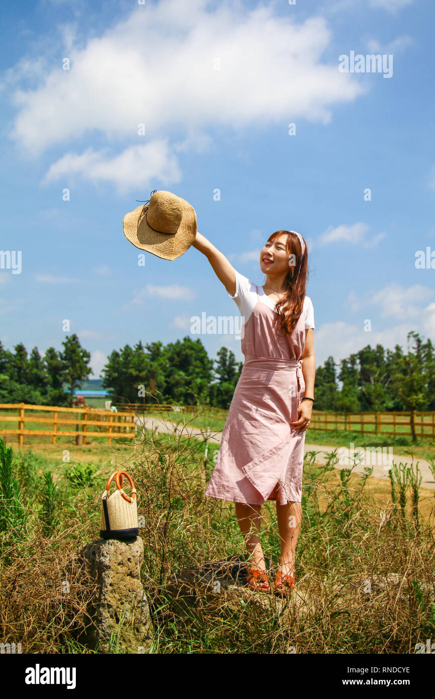 Asian giovane donna stretching la sua mano foratura un cappello per il cielo Foto Stock