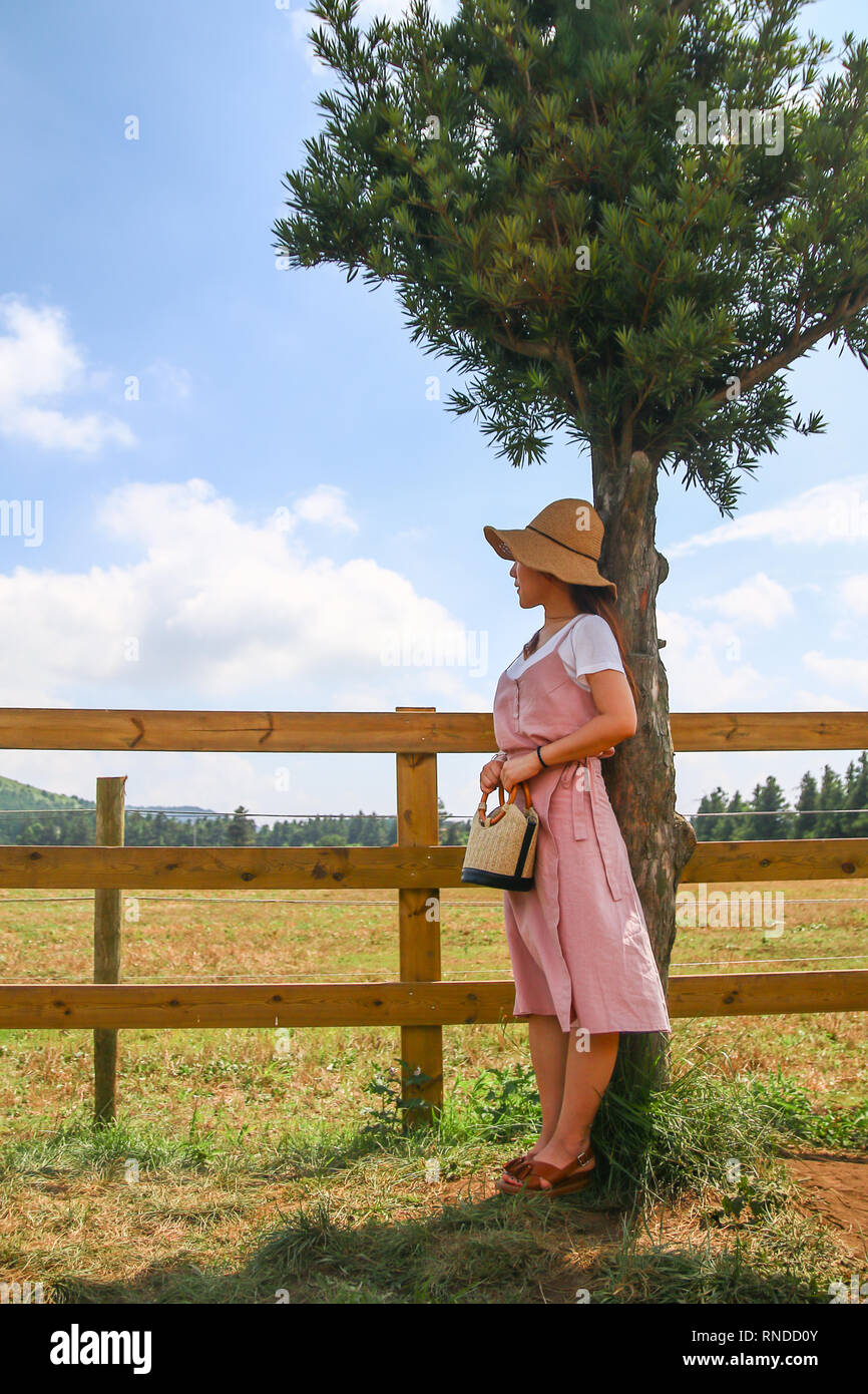 Asian giovane donna in attesa di una persona in piedi dalla riga nel ranch Foto Stock
