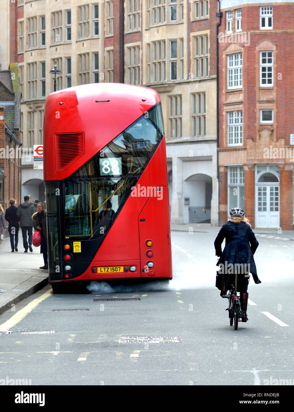 Londra, Inghilterra, Regno Unito. Ciclista il sorpasso di un autobus a due piani con uno Scarico molto fumoso, in Westminster Foto Stock