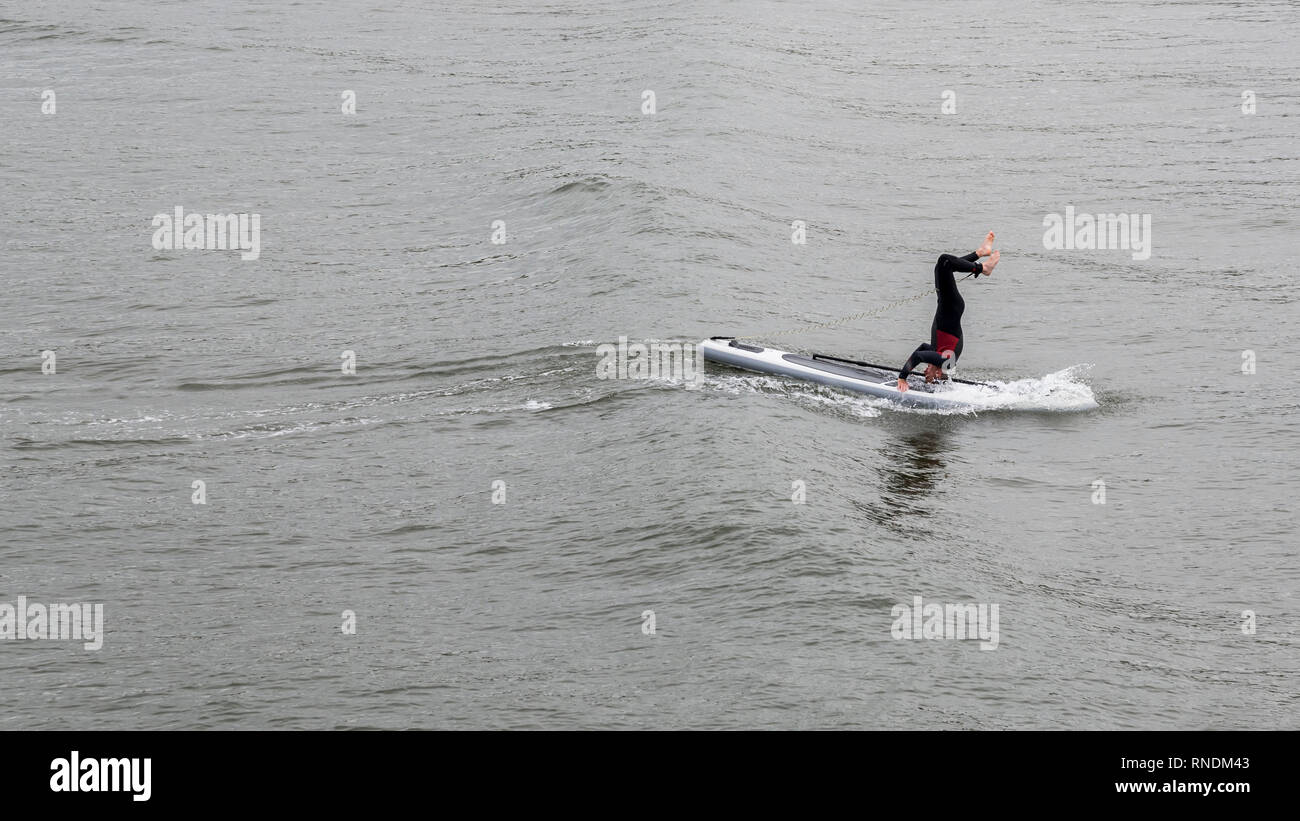 Surfer facendo una mano stand in mare a cambs, North Yorkshire, Inghilterra Foto Stock