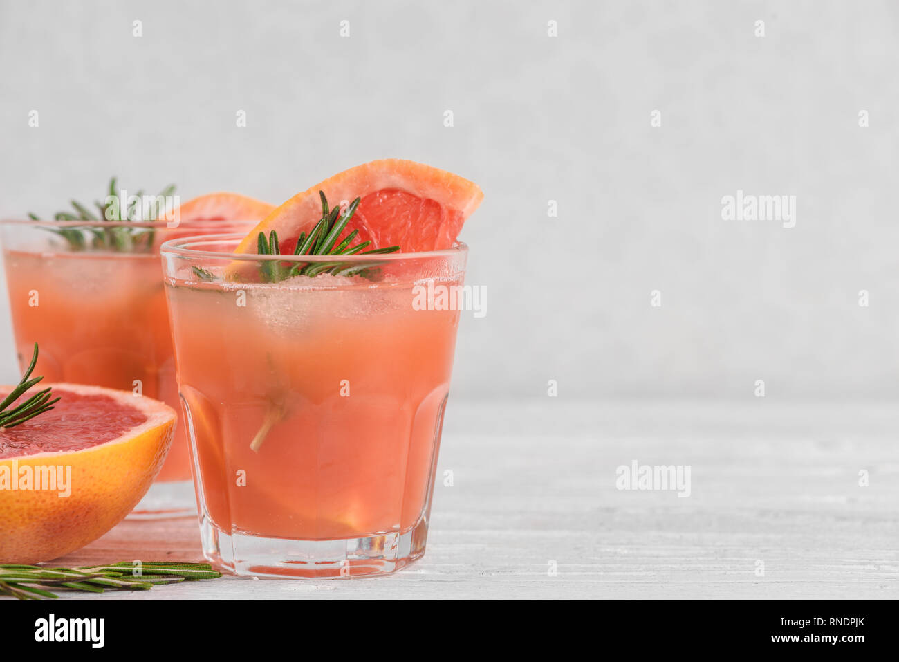 Succo di pompelmo fresco estate cocktail alcolici in bicchieri di ghiaccio e rosmarino su sfondo bianco. close up Foto Stock