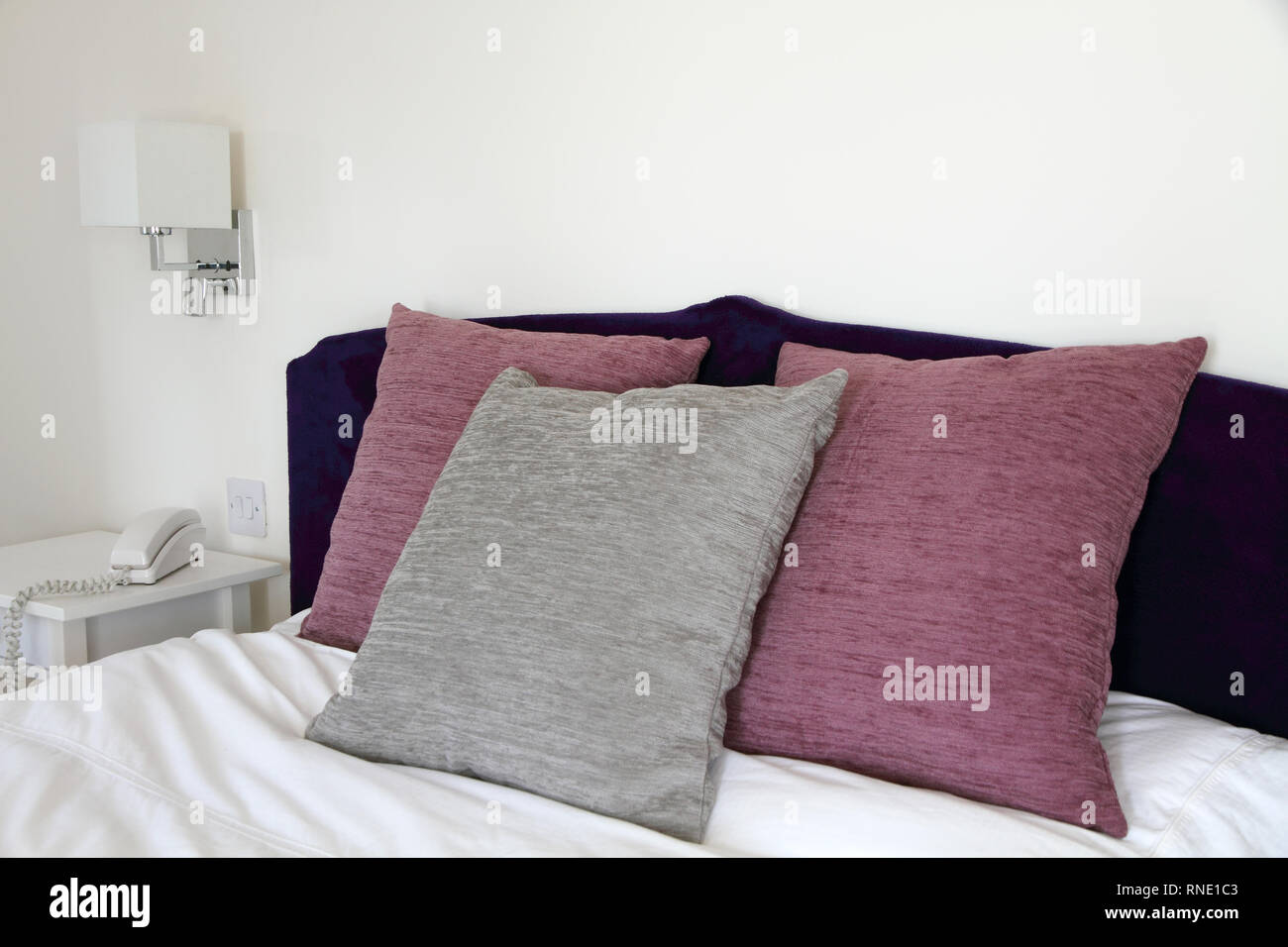 Testiera del letto con il grigio e lampone cuscini colorati Foto Stock