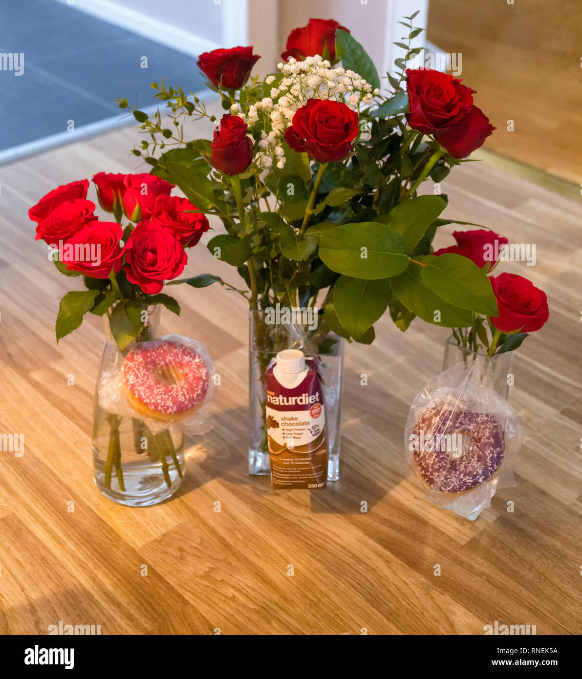 Tre mazzi di rose rosse e alcune chicche per la famiglia il giorno di San Valentino Foto Stock