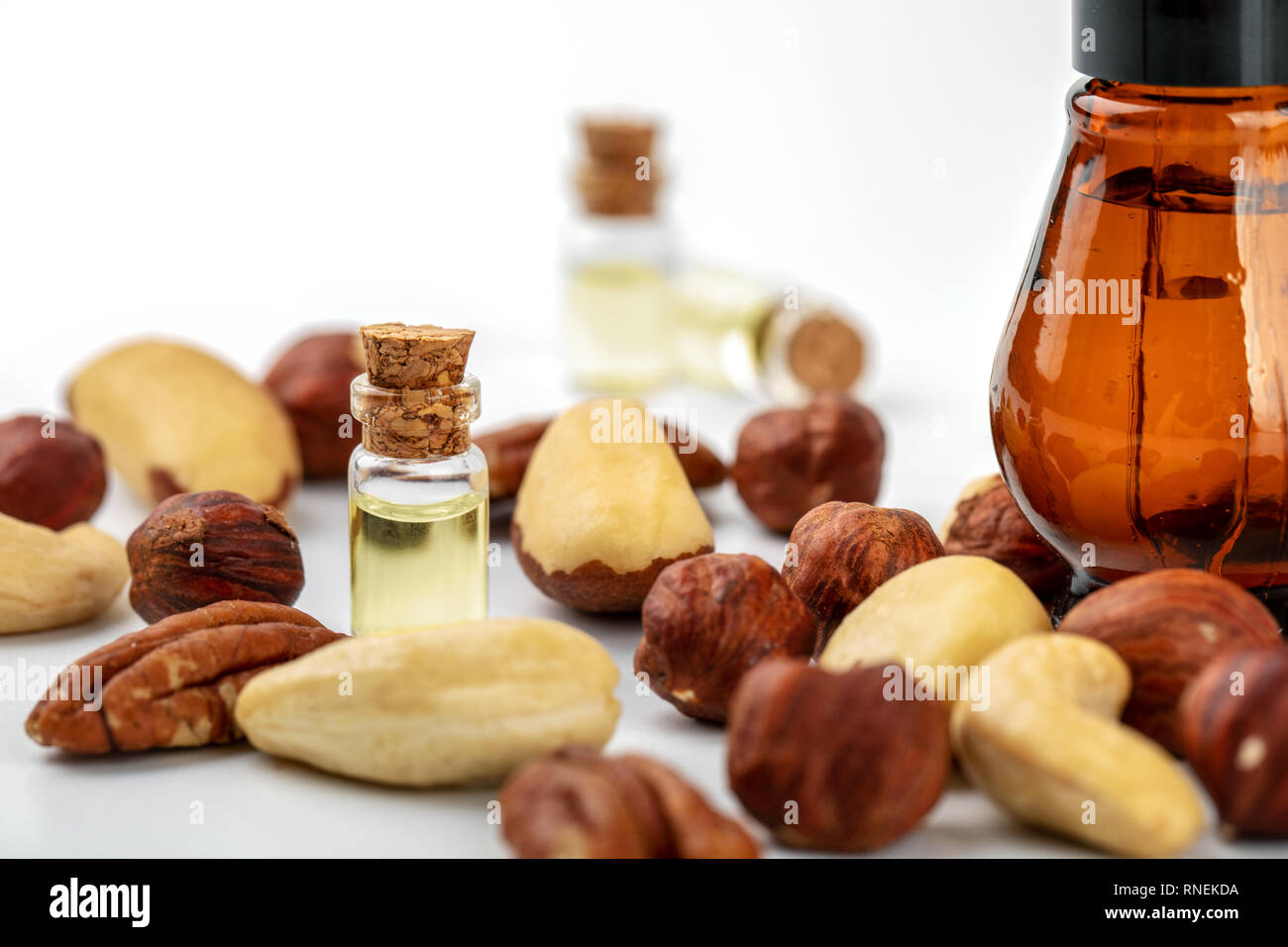 Dado di bottiglie di olio e varietà di dadi su bianco Foto Stock