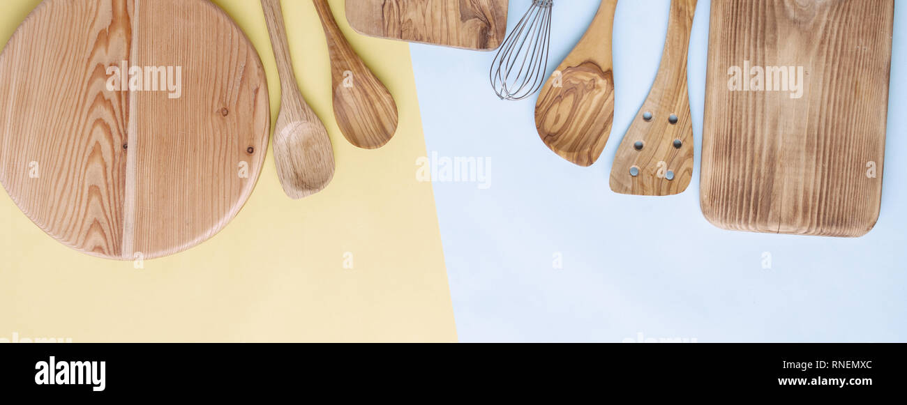 Foto dai toni utensili da cucina, per la preparazione di alimenti accessorises cottura, taglieri, mestoli, frusta sul blu e giallo tabella, vista dall'alto, il fuoco selettivo Foto Stock