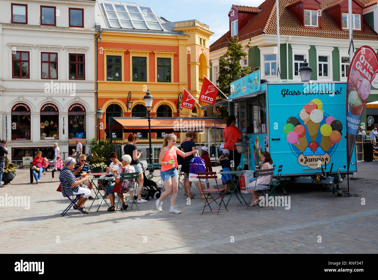 Ystad, Svezia - 26 Giugno 2018: persone che visitano un mobile di gelato chiosco vendita del marchio Ottoglass con posti a sedere all'aperto presso la piazza della città. Foto Stock