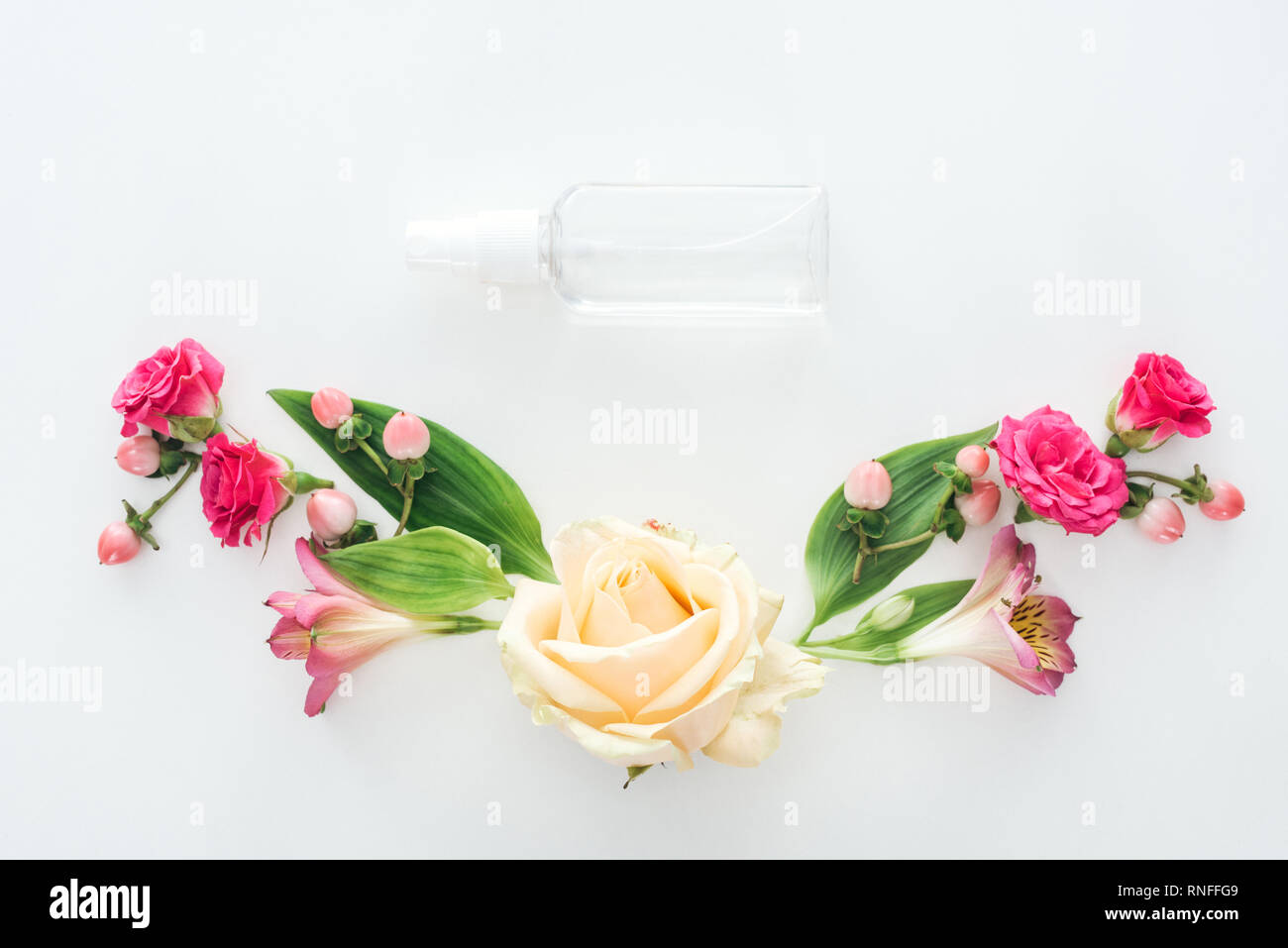 Vista superiore della composizione con alstroemeria, rose, bacche e svuotare la bottiglia spray su sfondo bianco Foto Stock