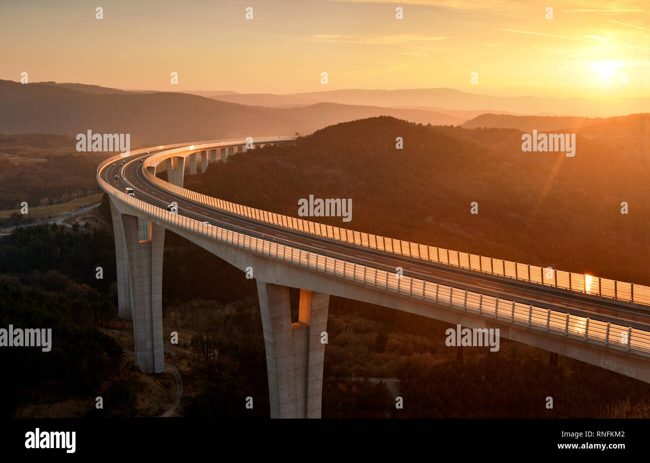 Vetture guida su un viadotto autostradale al bel tramonto Foto Stock
