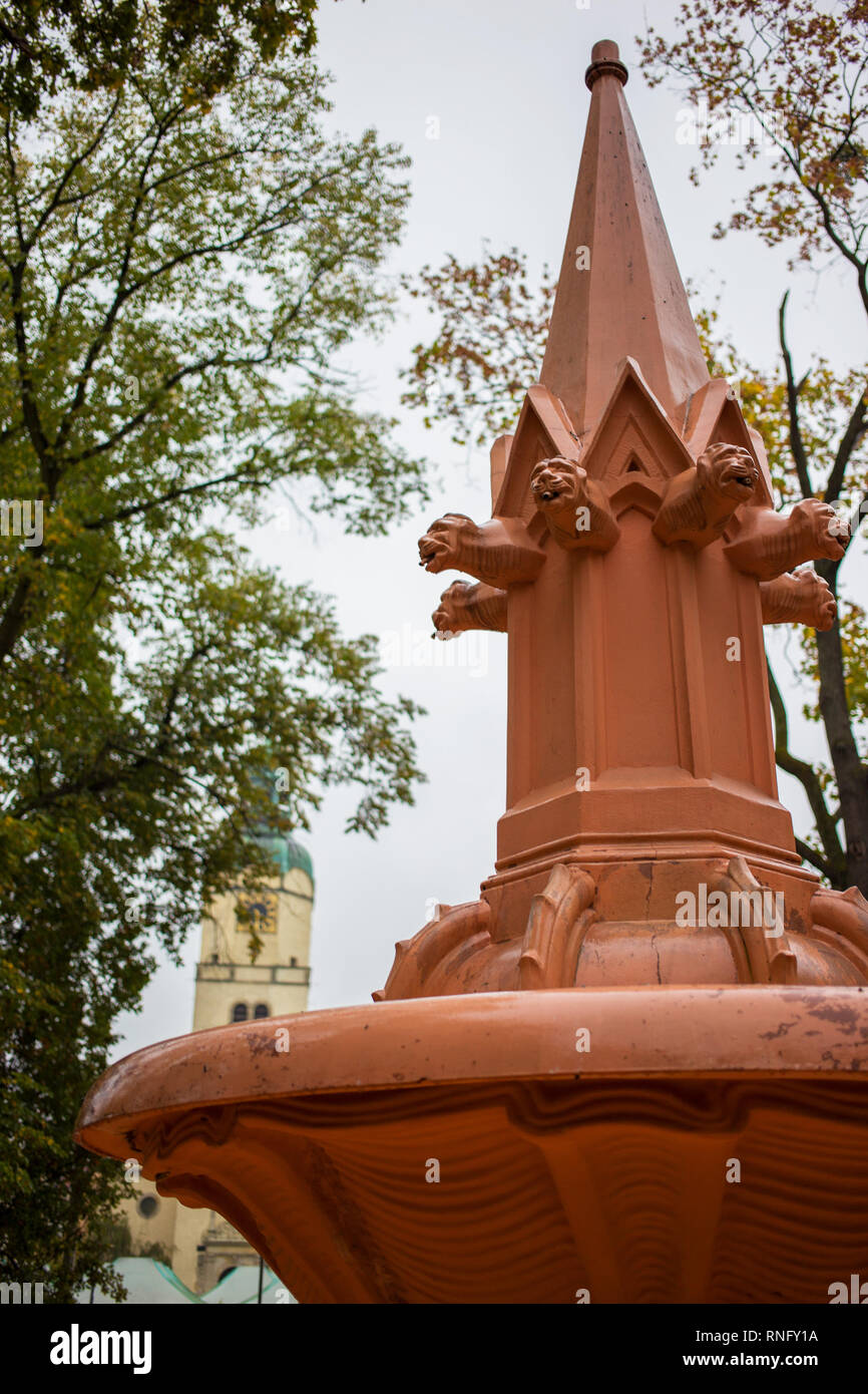 Colore arancio fontana situata nel parco vicino mercato Wilda a Poznan ha acqua spento, vi è il campanile di una chiesa in background Foto Stock