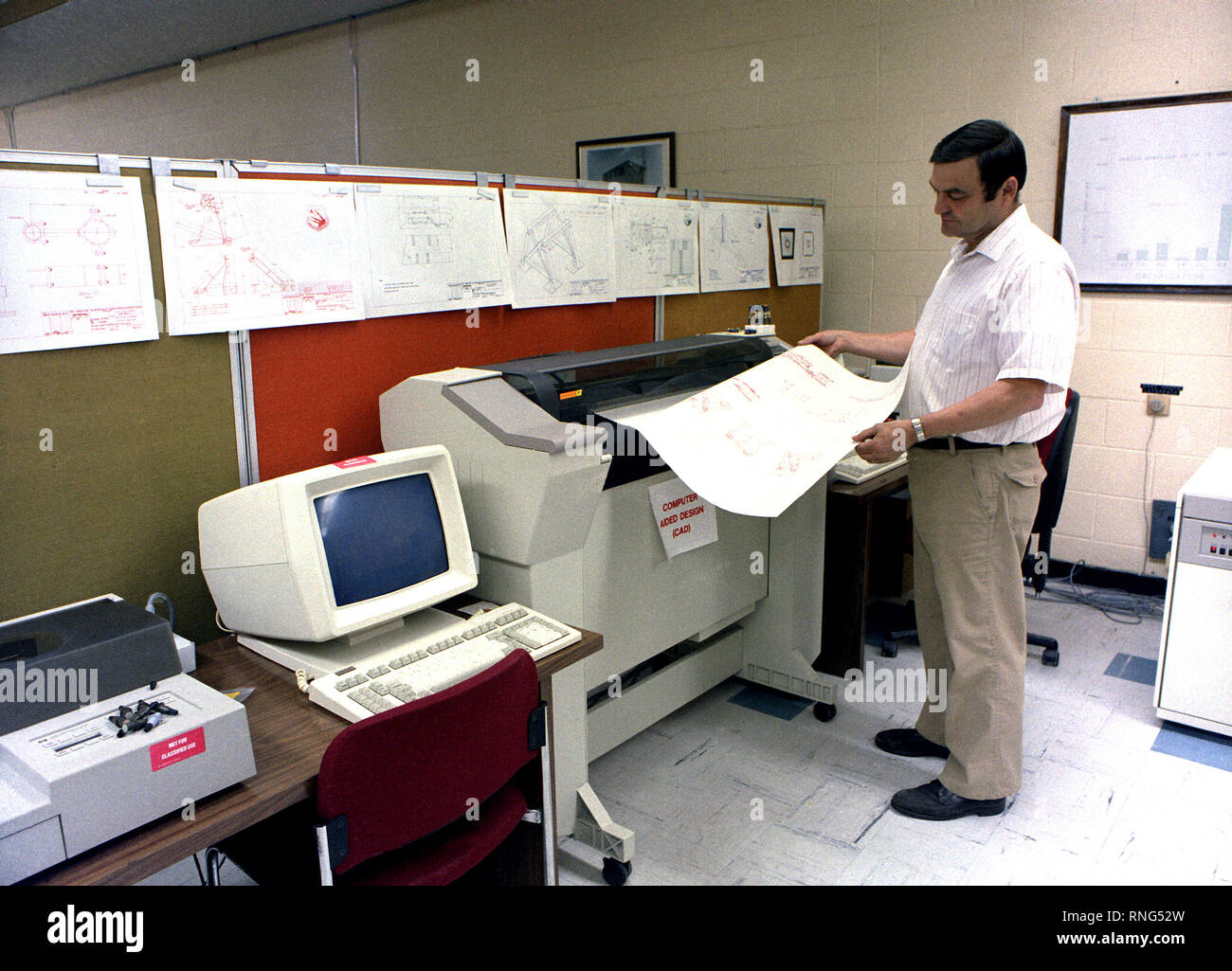 Un ingegnere controlla una stampa come egli utilizza il Computer Aided Design (CAD) sistema per sviluppare il sistema di montaggio per la sezione di coda del B-1 bombardiere. Foto Stock