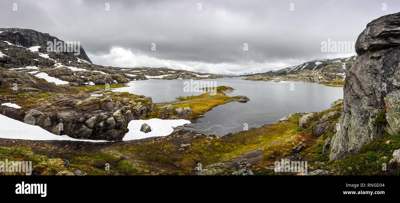 Tipico paesaggio norvegese con montagne innevate e chiaro lago vicino il Trolltunga rock - più spettacolare e famosa scenic cliff in Norvegia Foto Stock