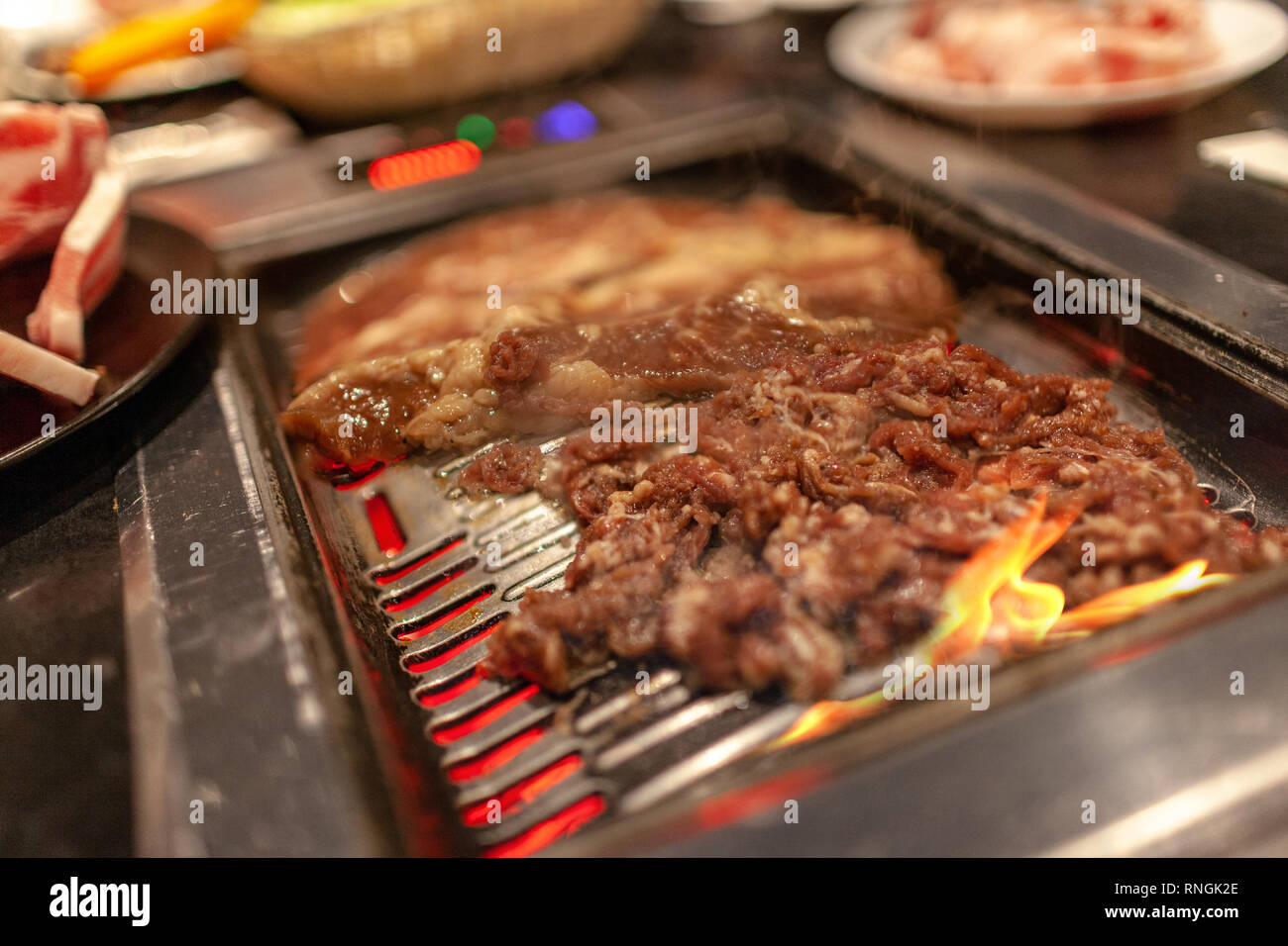Korean barbecue in stile con succosa carne di manzo e le nervature brevi sulla stufa calda la piastra con il fuoco e con emissione di fumi di cottura. Foto Stock