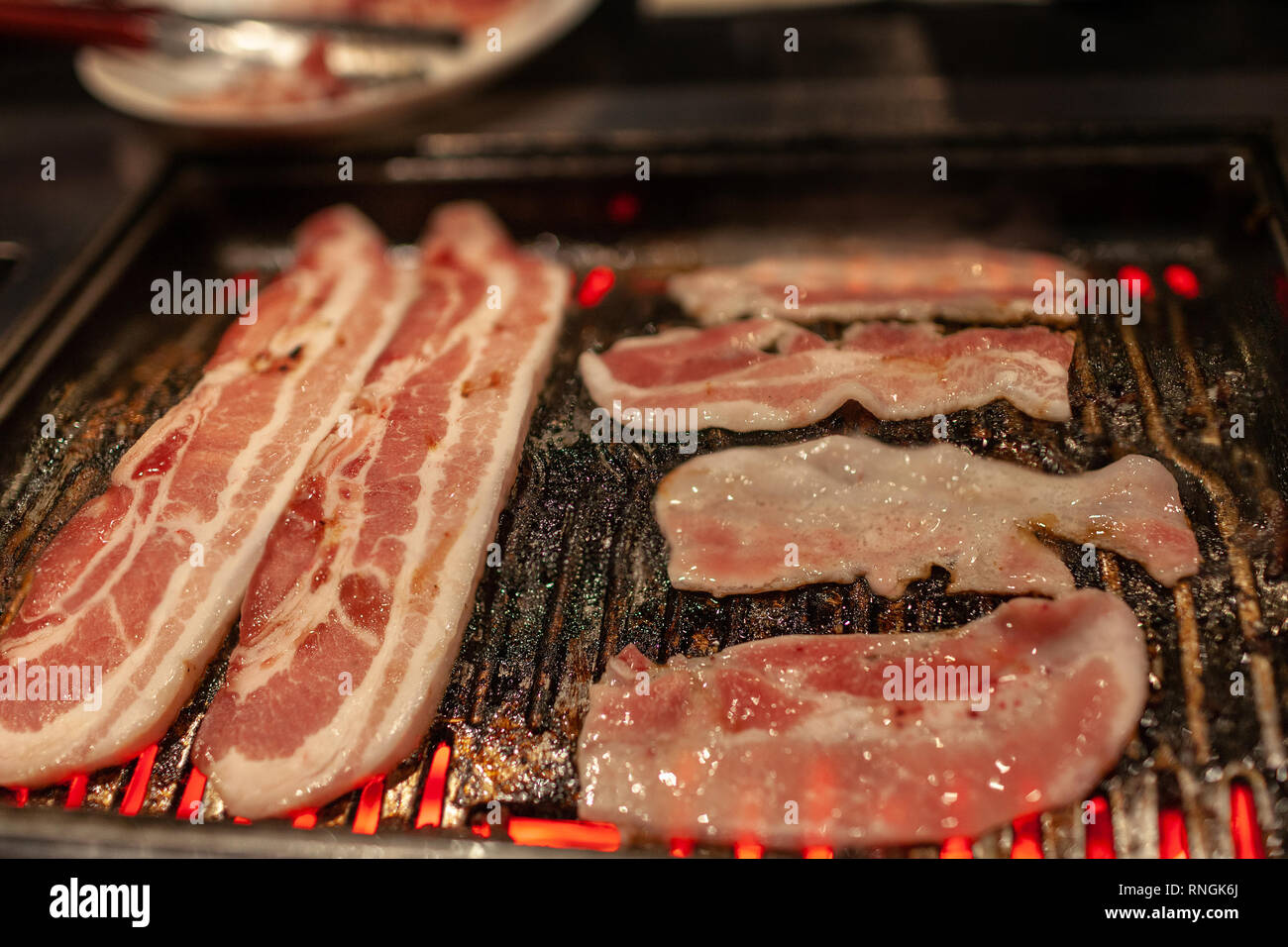 Korean barbecue in stile con juicy crudo marinato pancetta di maiale carne sulla stufa calda piastra. Foto Stock