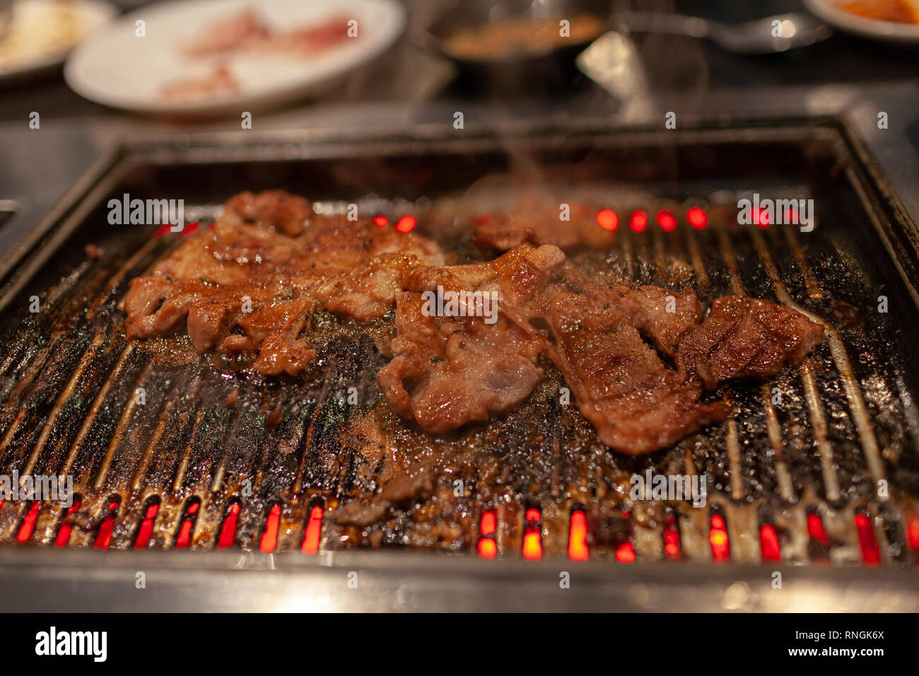 Korean barbecue in stile con succosa carne di manzo marinato sulla stufa calda piastra con emissione di fumi di cottura. Foto Stock