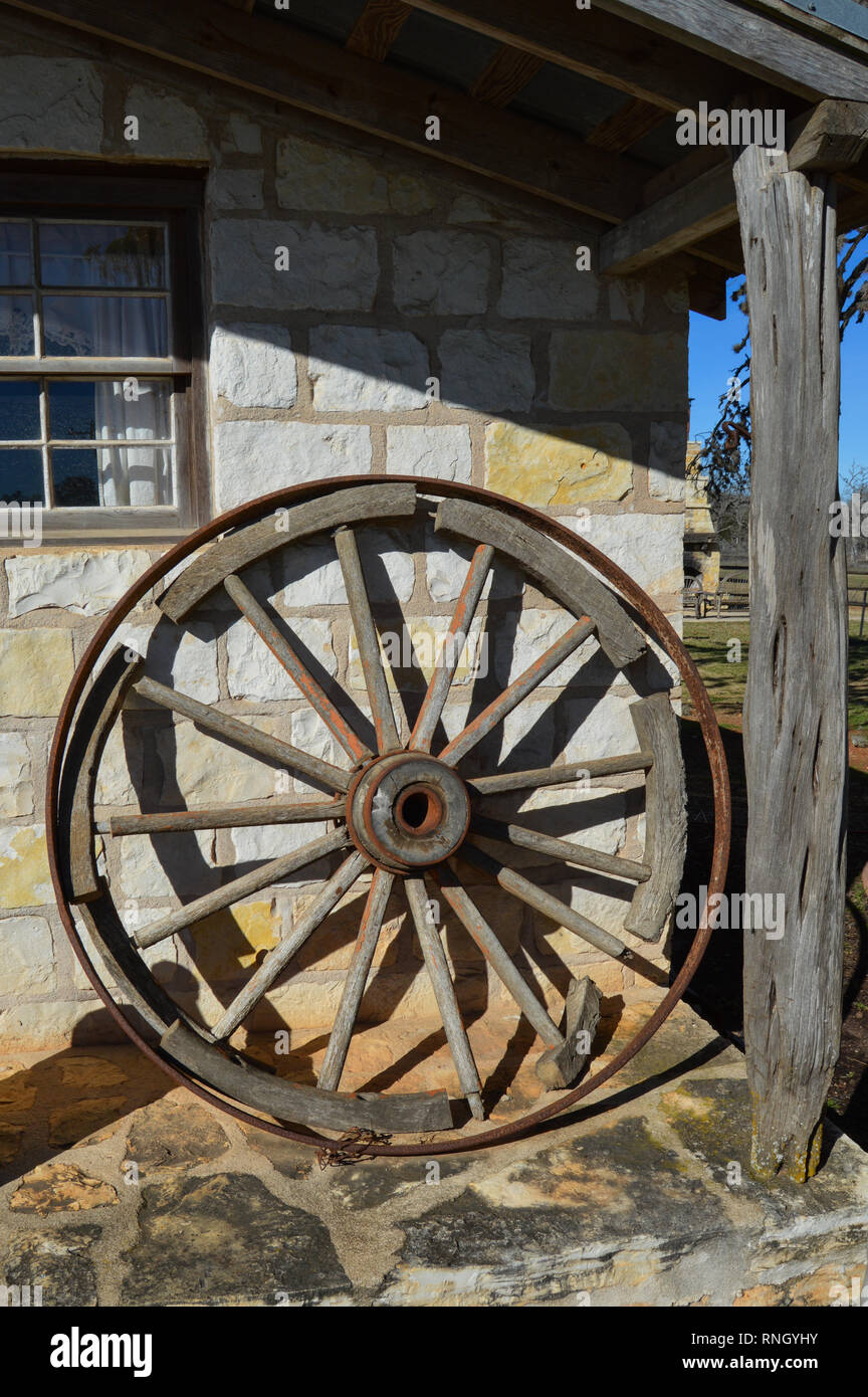 Antiquariato ruota di carro appoggiato su di un vecchio western house. Foto Stock