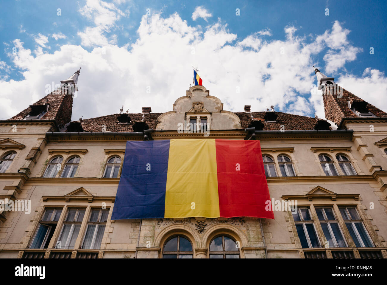 Una gigantesca bandiera rumena si blocca all'esterno di un edificio in Sighișoara, Transilvania, Romania Foto Stock