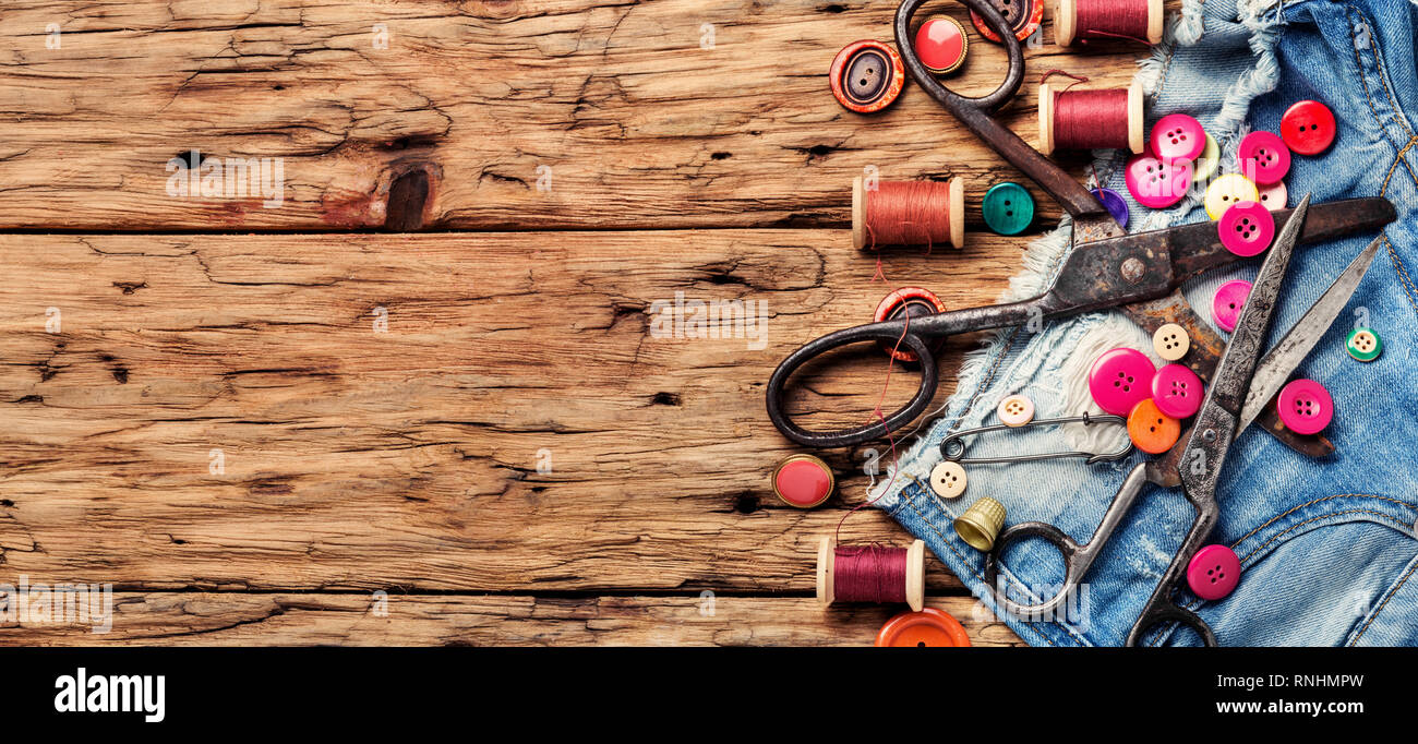 Bobine di filo di base e strumenti di cucitura sul piano portapaziente in legno Foto Stock