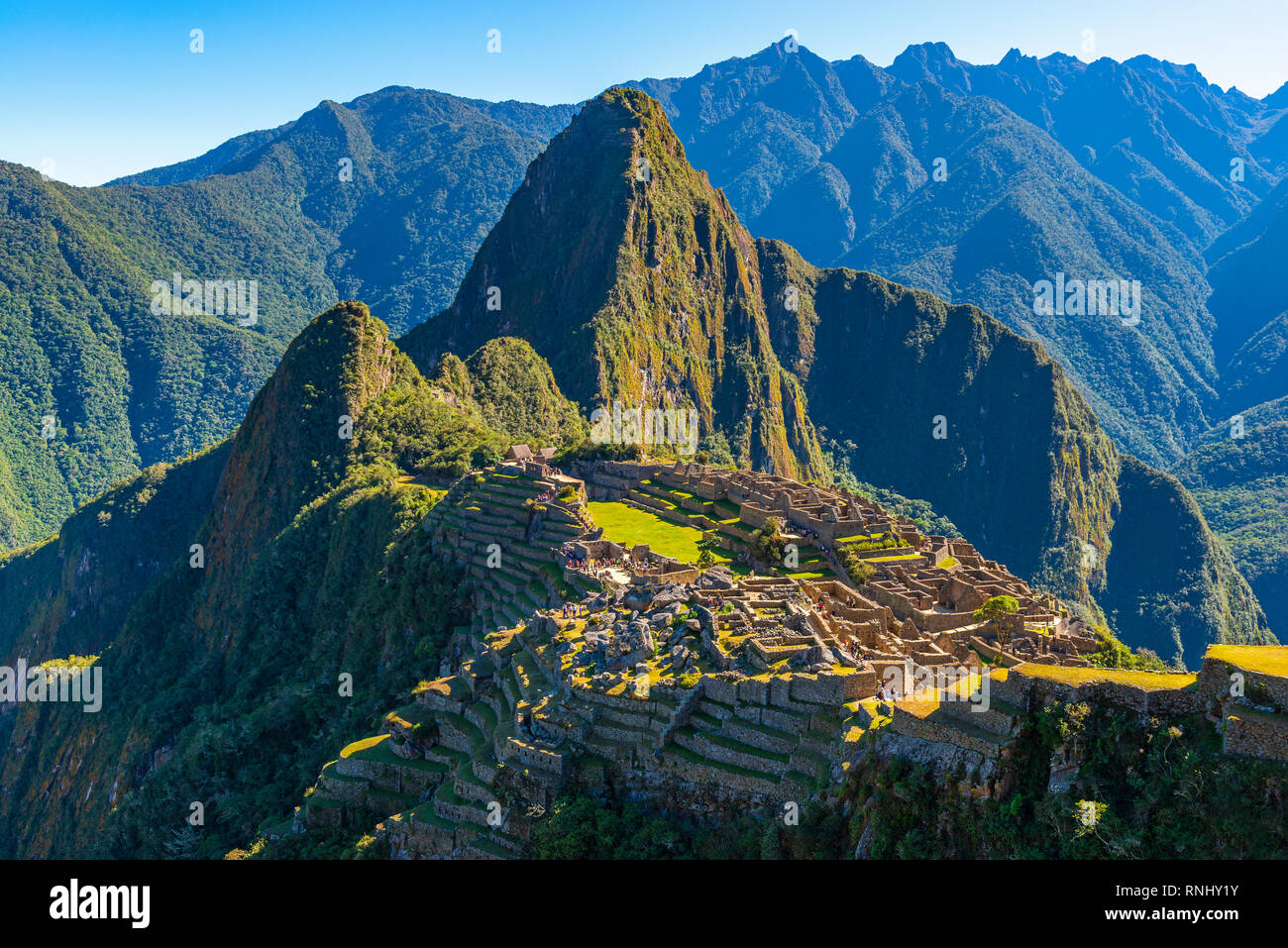 I primi raggi del sole che splende su l'Inca città perduta di Machu Picchu con il suo verde agricoltura terrazze, alloggiamento e Huayna Picchu picco vicino a Cusco, Perù. Foto Stock