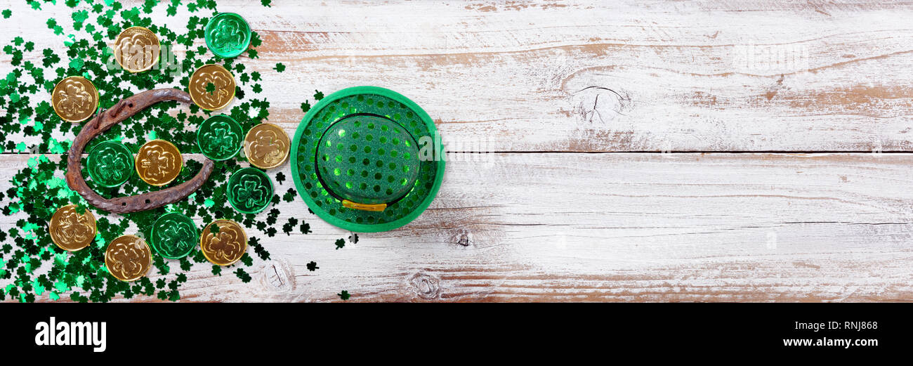 Colore verde brillante shamrock con monete d oro, cappello e rusty a ferro di cavallo per San Patrizio giorno su bianco rustico sfondo di legno Foto Stock