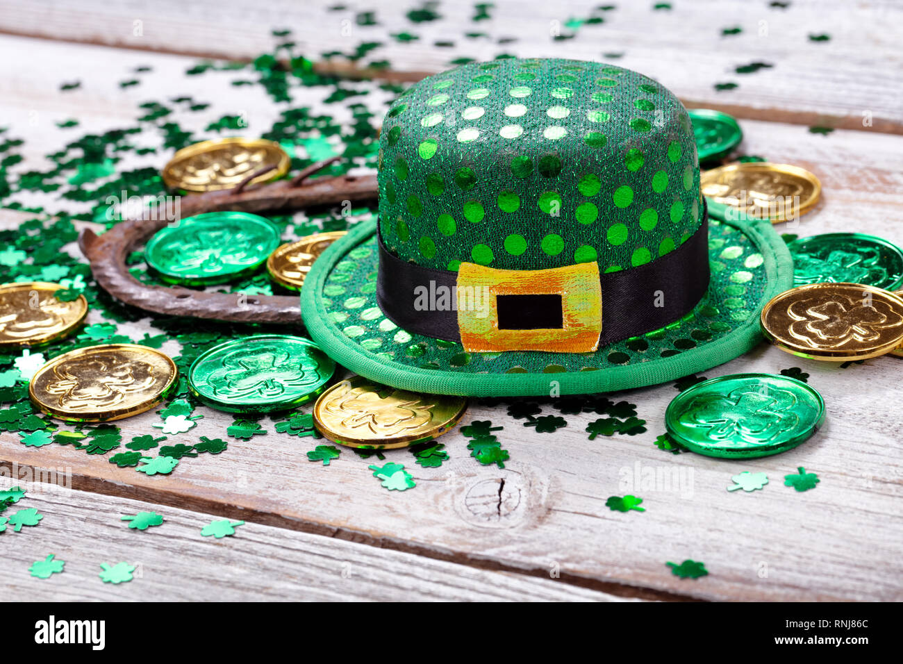 Colore verde brillante con cappello di monete d'oro, shamrock e rusty a ferro di cavallo per San Patrizio giorno su bianco rustico sfondo di legno in stretta fino formato Foto Stock